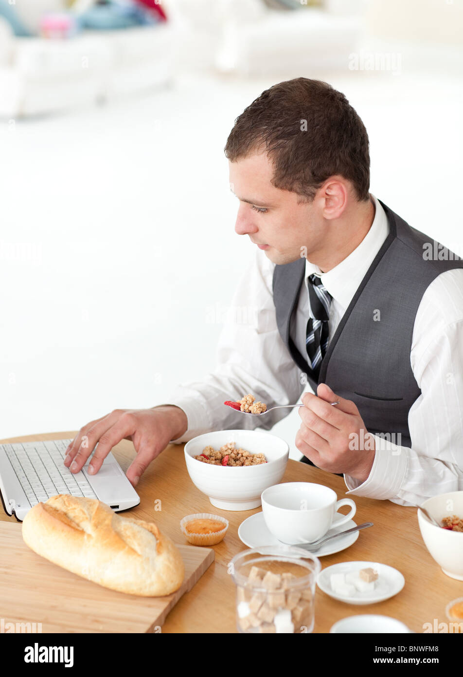 Junger Geschäftsmann mit einem Laptop beim Frühstück Stockfoto