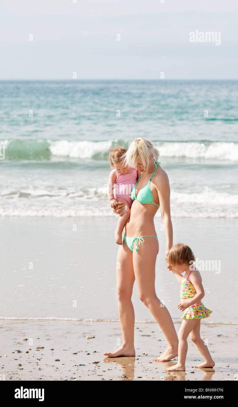 Eine junge Mutter zu Fuß am Strand mit ihren Kindern Stockfoto