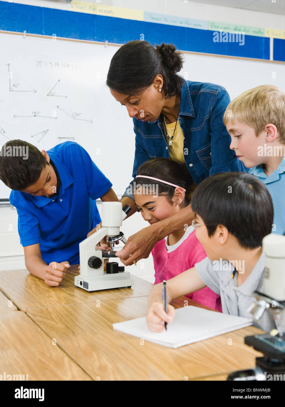 Lehrer Schüler Mikroskop im Science Lab verwenden Stockfoto