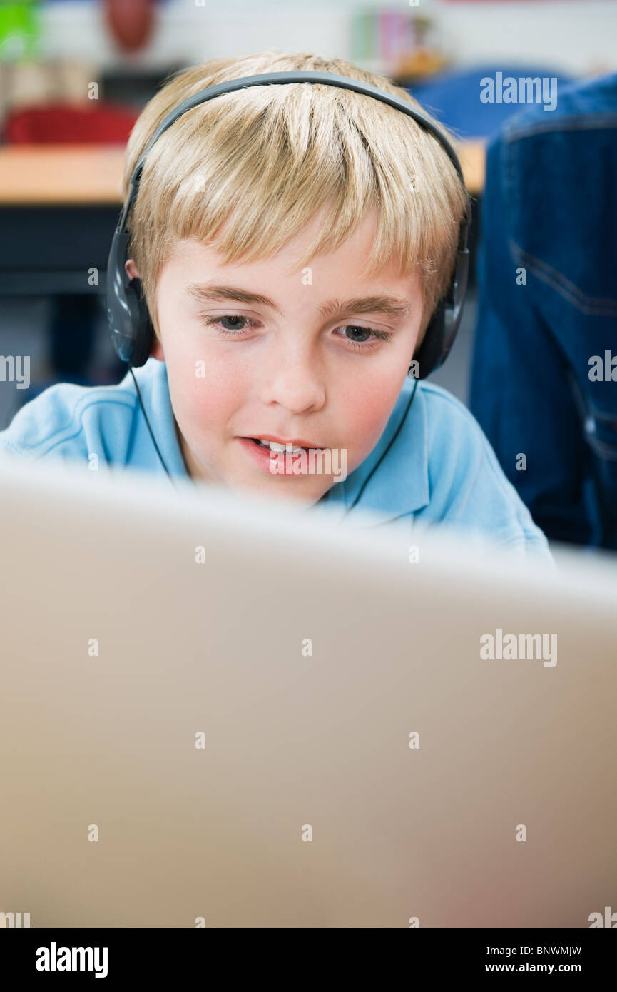 Elementare Student mit Kopfhörern im Klassenzimmer Stockfoto