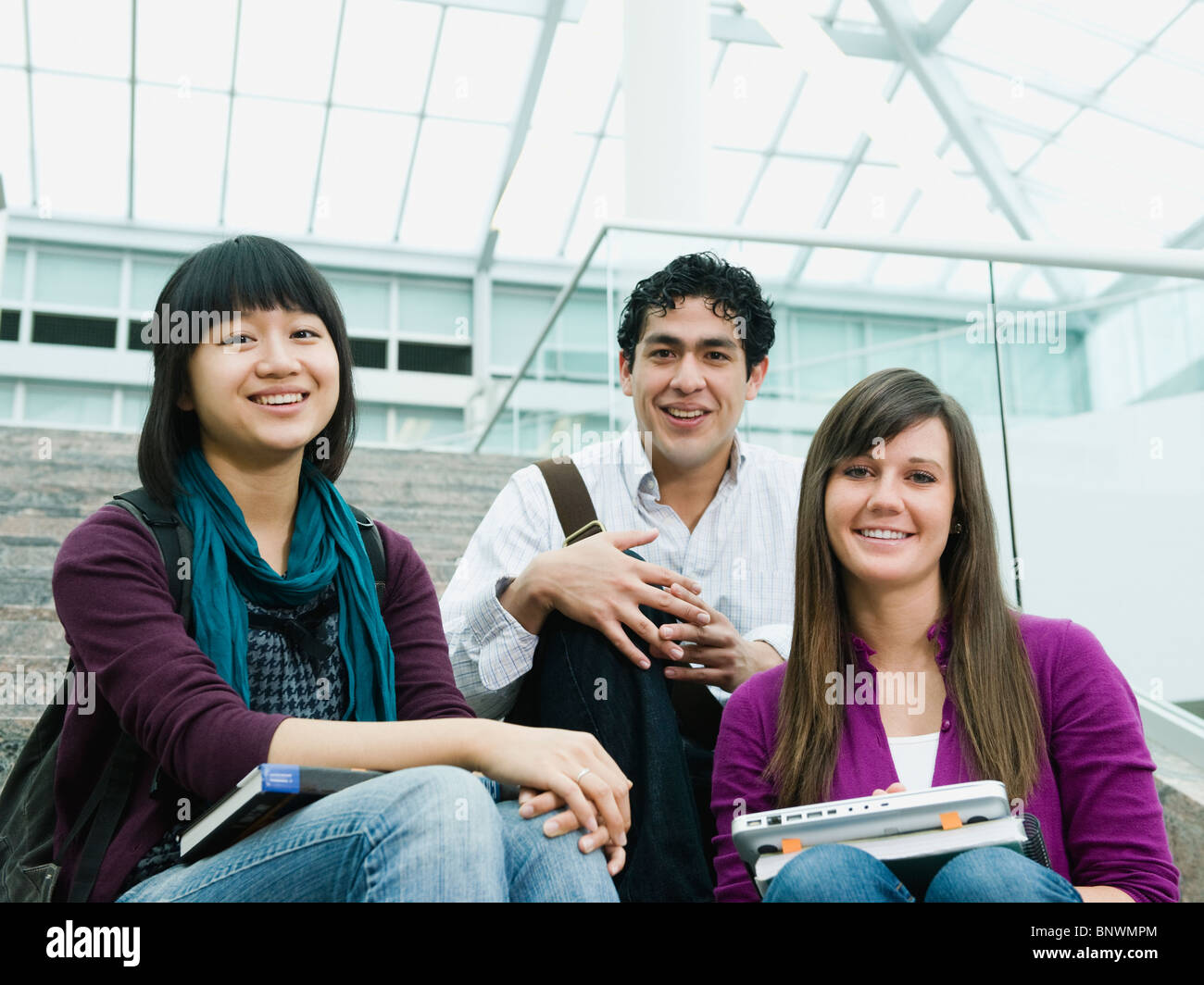 College-Studenten sitzen auf den Stufen vor der Bibliothek Stockfoto