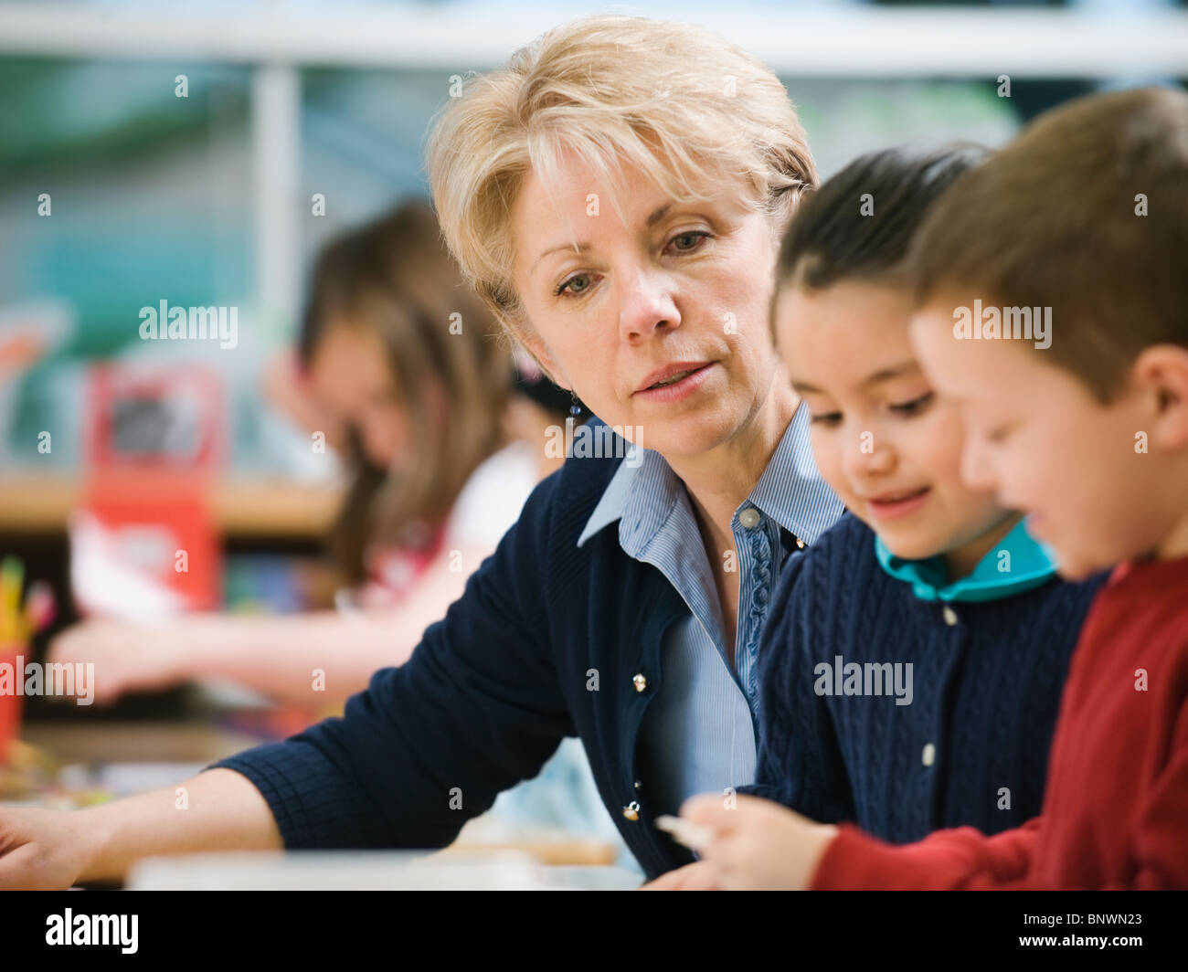 Lehrer mit Kindergarten Studenten am Tisch sitzen Stockfoto