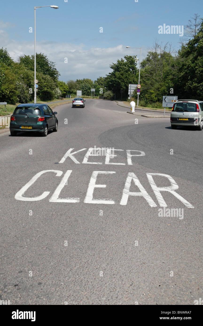 Vorbeifahrende Autos in der Nähe einer "Keep Clear" Straße Kennzeichnung in Bridport, Großbritannien. Stockfoto