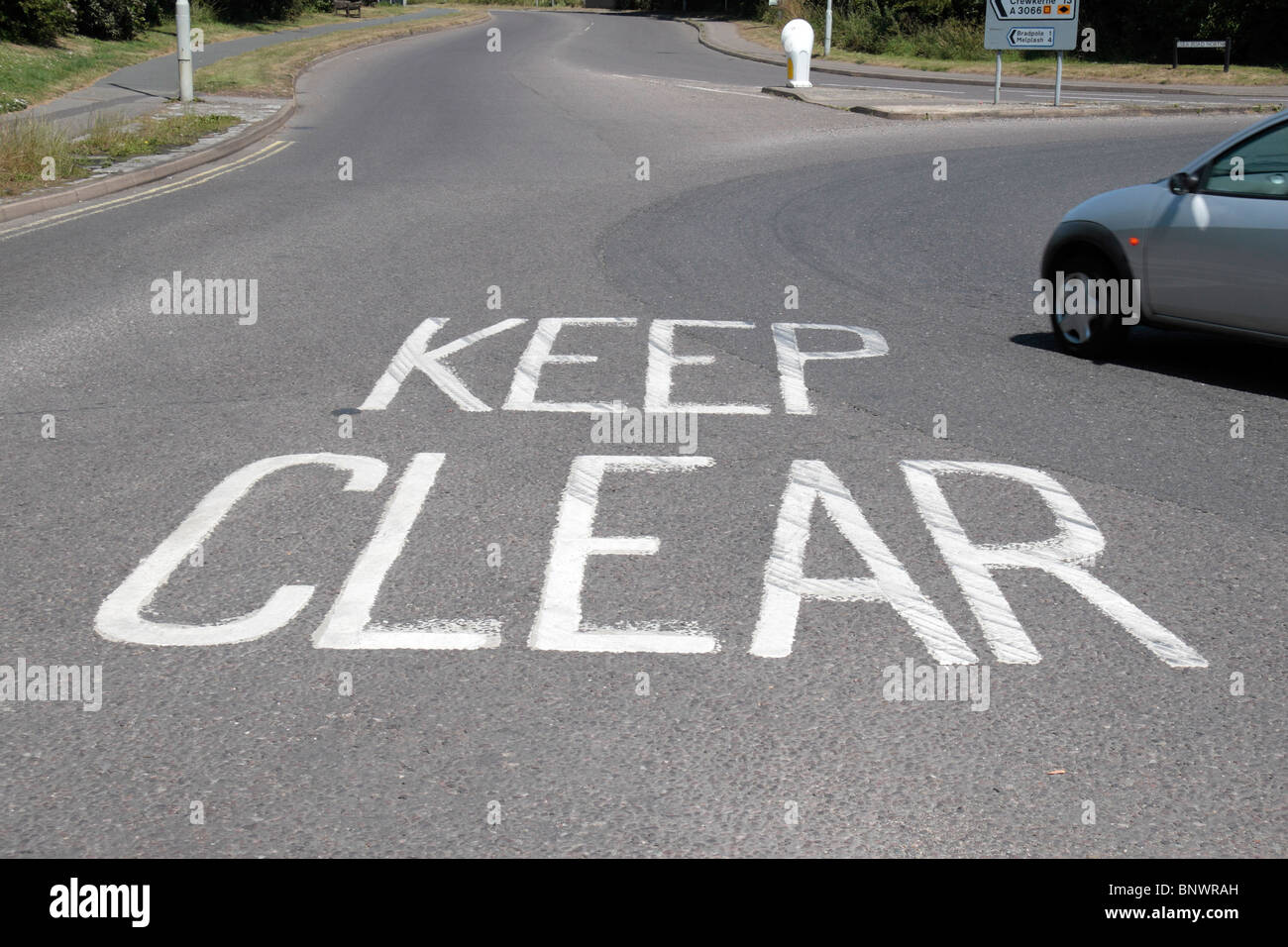 Vorbeifahrende Autos in der Nähe einer "Keep Clear" Straße Kennzeichnung in Bridport, Großbritannien. Stockfoto