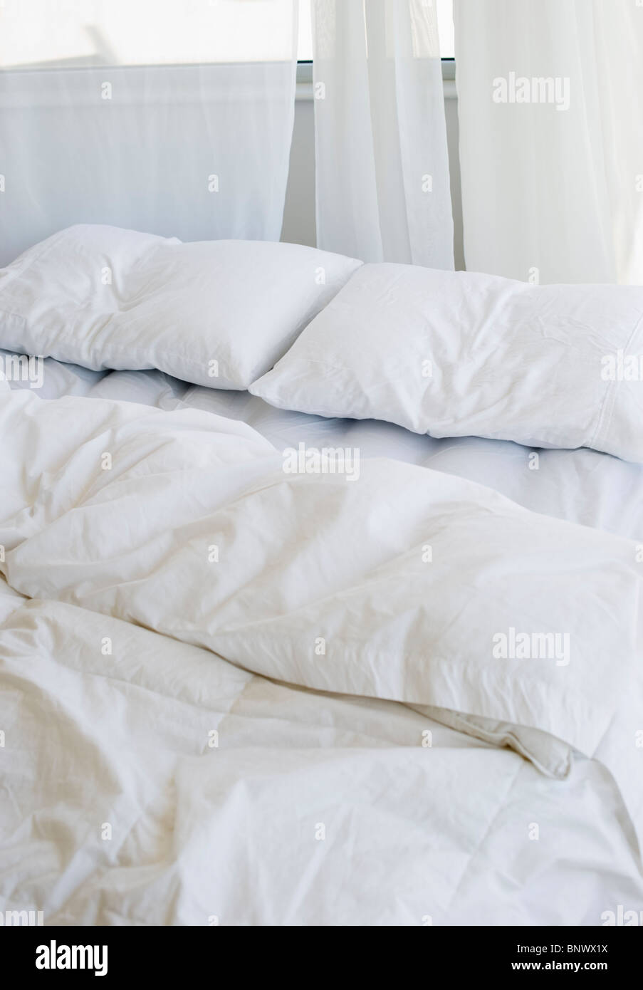 Bett mit weißer Bettwäsche Stockfoto