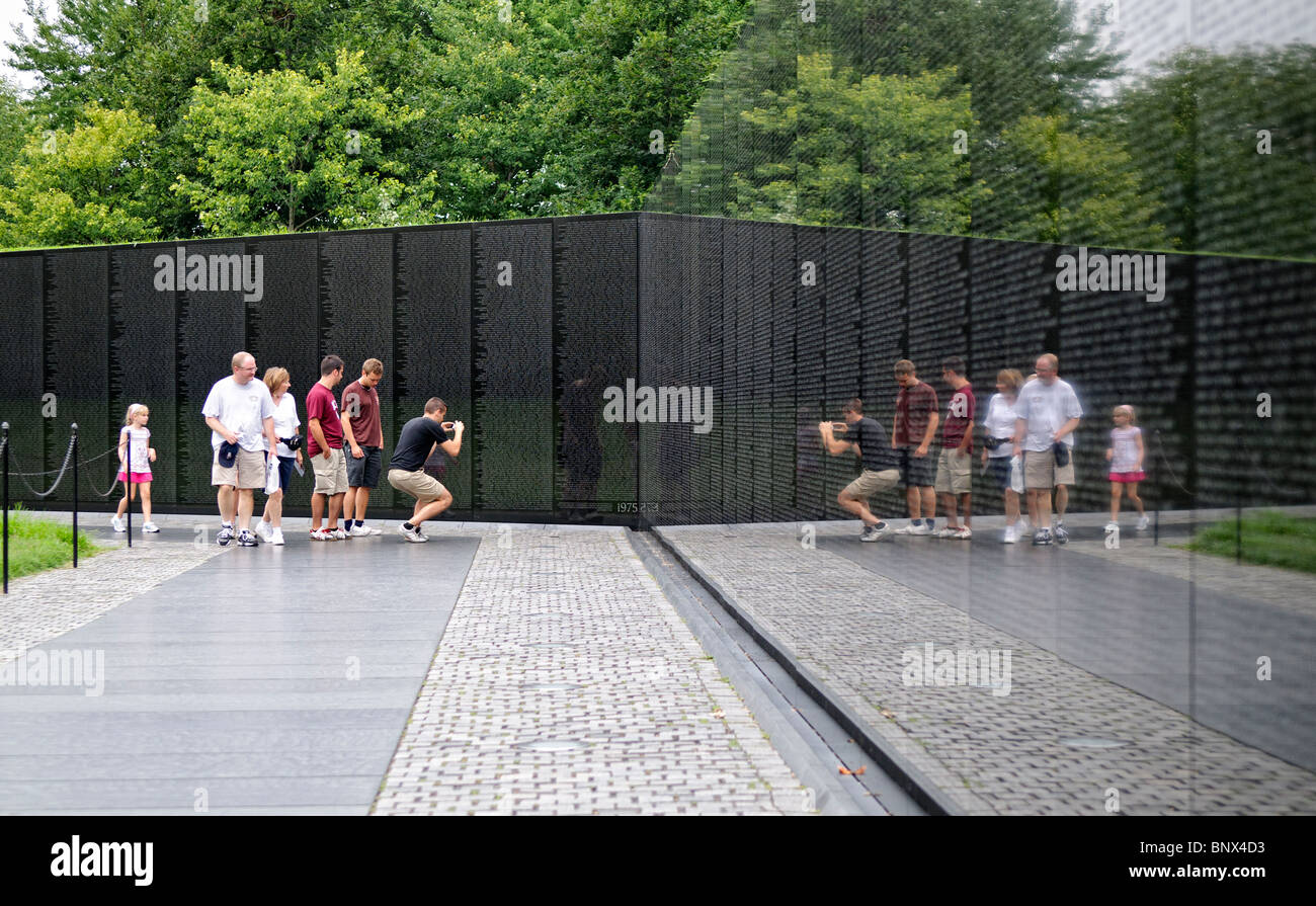 Vietnam Veterans Memorial Wall Washington DC // WASHINGTON DC – Besucher beobachten das Vietnam Veterans Memorial auf der National Mall in Washington DC. Das 1982 von Maya Lin entworfene und geweihte Denkmal besteht aus zwei Wänden aus schwarzem Granit, die die Namen von mehr als 58.000 Amerikanern zeigen, die im Vietnamkrieg gestorben sind oder vermisst bleiben. Die polierte Oberfläche reflektiert die Besucher beim Betrachten der chronologisch angeordneten Namen auf der V-förmigen Gedenkstätte. Stockfoto