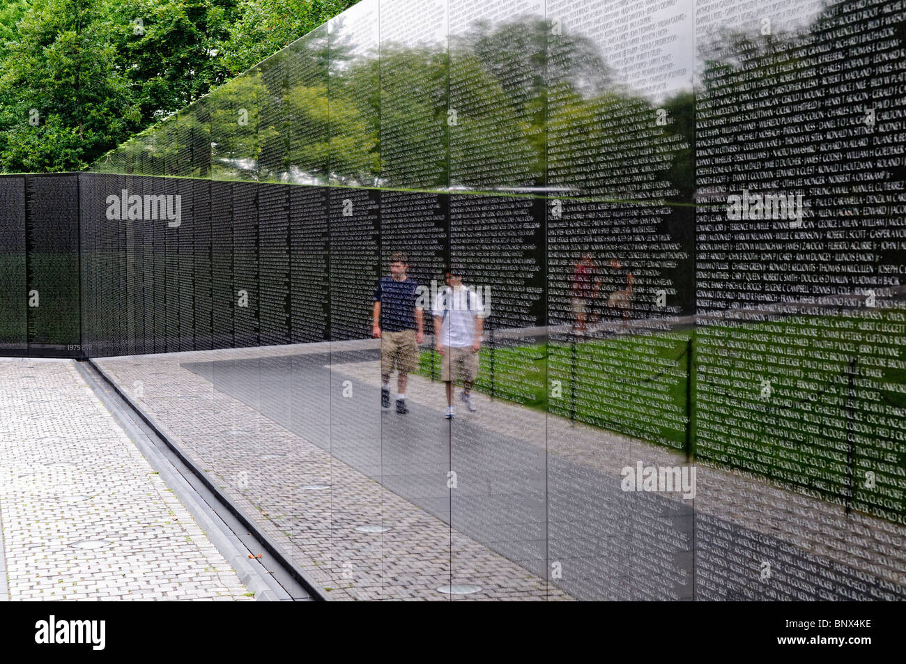 Vietnam Veterans Memorial Wall Washington DC // WASHINGTON DC – Besucher beobachten das Vietnam Veterans Memorial auf der National Mall in Washington DC. Das 1982 von Maya Lin entworfene und geweihte Denkmal besteht aus zwei Wänden aus schwarzem Granit, die die Namen von mehr als 58.000 Amerikanern zeigen, die im Vietnamkrieg gestorben sind oder vermisst bleiben. Die polierte Oberfläche reflektiert die Besucher beim Betrachten der chronologisch angeordneten Namen auf der V-förmigen Gedenkstätte. Stockfoto