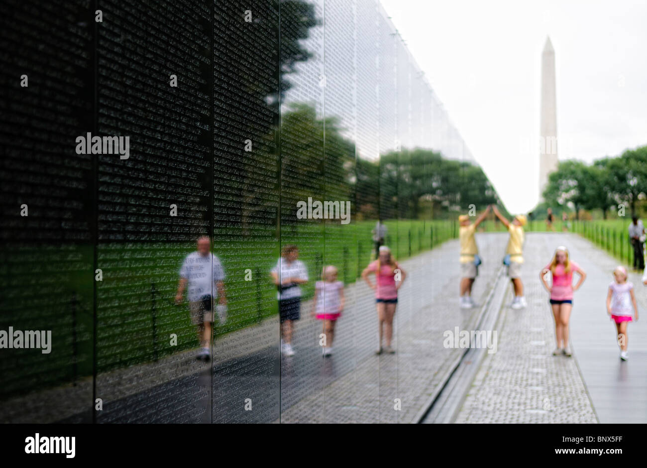 Vietnam Veterans Memorial Visitors Washington DC // WASHINGTON DC – Besucher beobachten das Vietnam Veterans Memorial auf der National Mall in Washington DC. Das 1982 von Maya Lin entworfene und geweihte Denkmal besteht aus zwei Wänden aus schwarzem Granit, die die Namen von mehr als 58.000 Amerikanern zeigen, die im Vietnamkrieg gestorben sind oder vermisst bleiben. Die polierte Oberfläche reflektiert die Besucher beim Betrachten der chronologisch angeordneten Namen auf der V-förmigen Gedenkstätte. Stockfoto