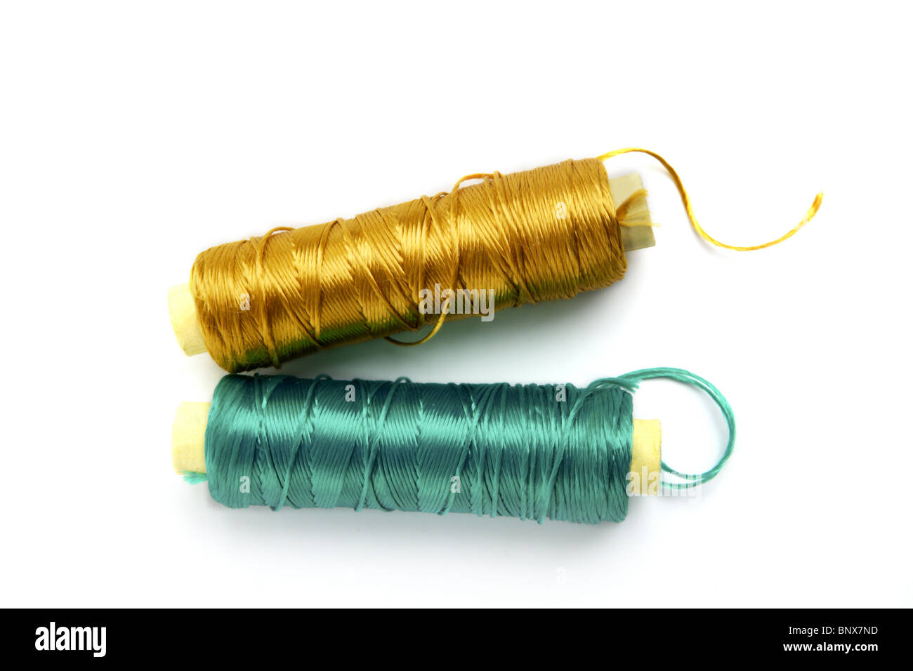 metallische Rayon Faden Fadenspule in grünen und goldenen Farben auf weiß Stockfoto