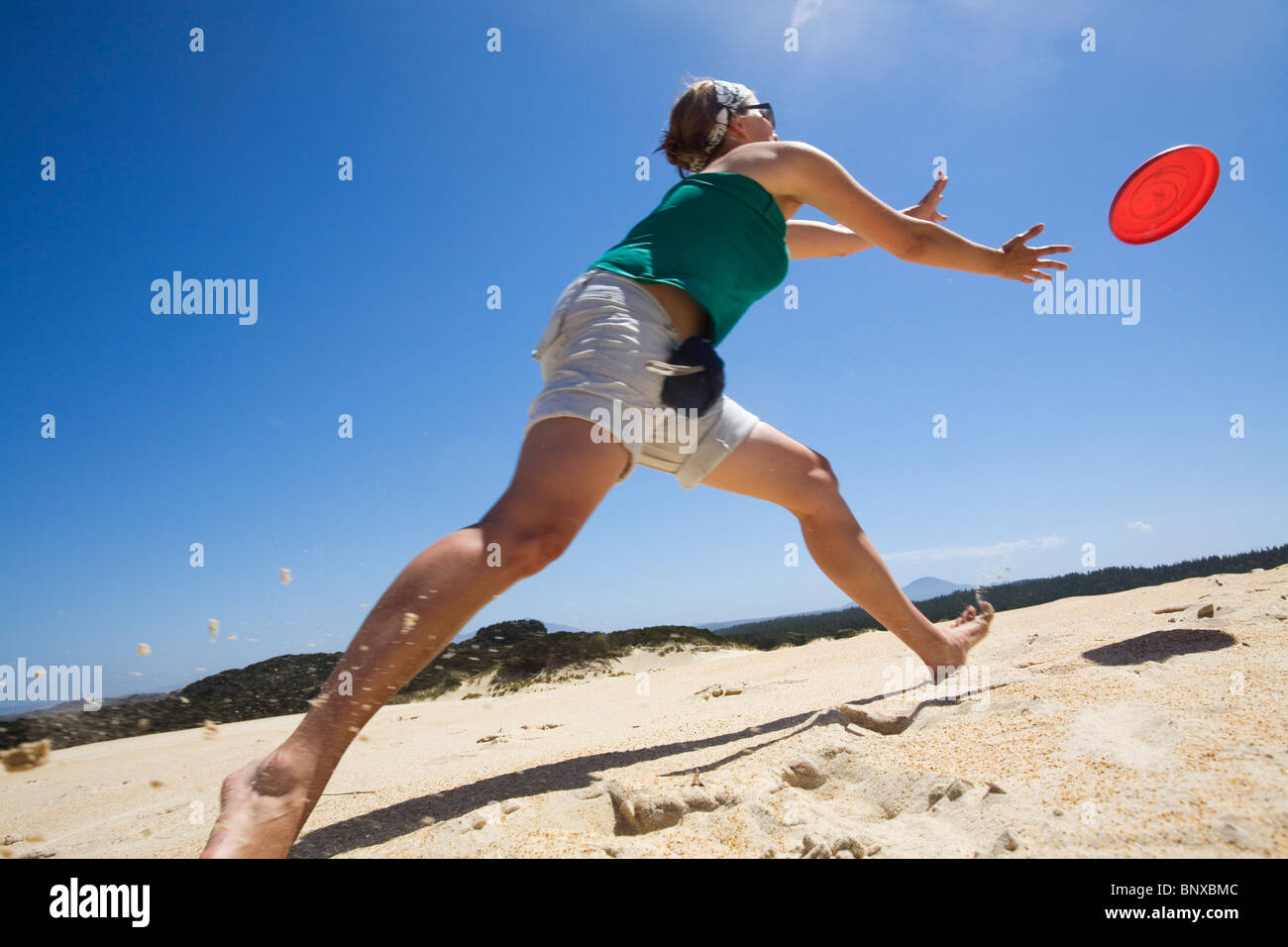 Frau eine Frisbee zu werfen, auf dem Sand der Dünen Henty, in der Nähe von Strahan, Tasmanien, Australien Stockfoto