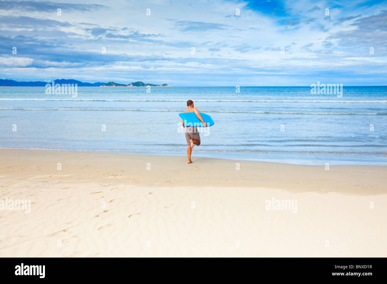 Mann mit Bodyboard am tropischen Strand Stockfoto