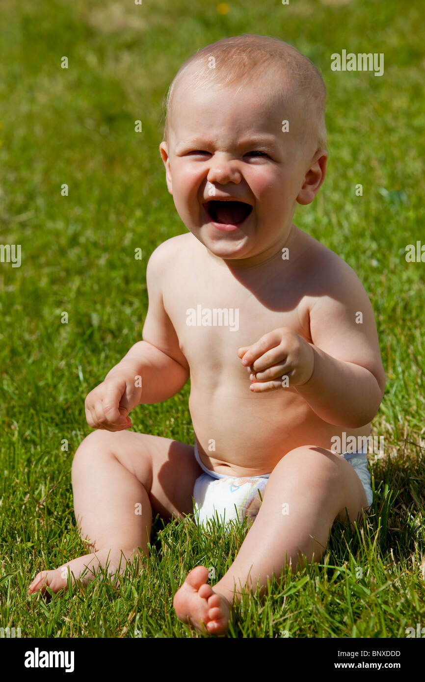Kleine Baby-Junge in Windeln sitzen auf Gras- und Lauging Stockfoto