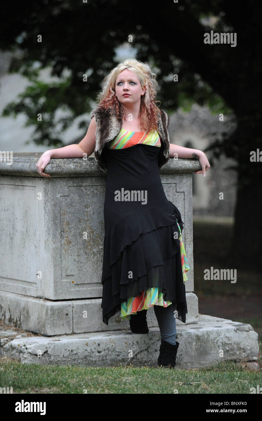 Blondine mit Avant-Garde-Frisur gegen Grab im Friedhof gotischen Stil der Mode Kleid ziemlich Modell Stockfoto