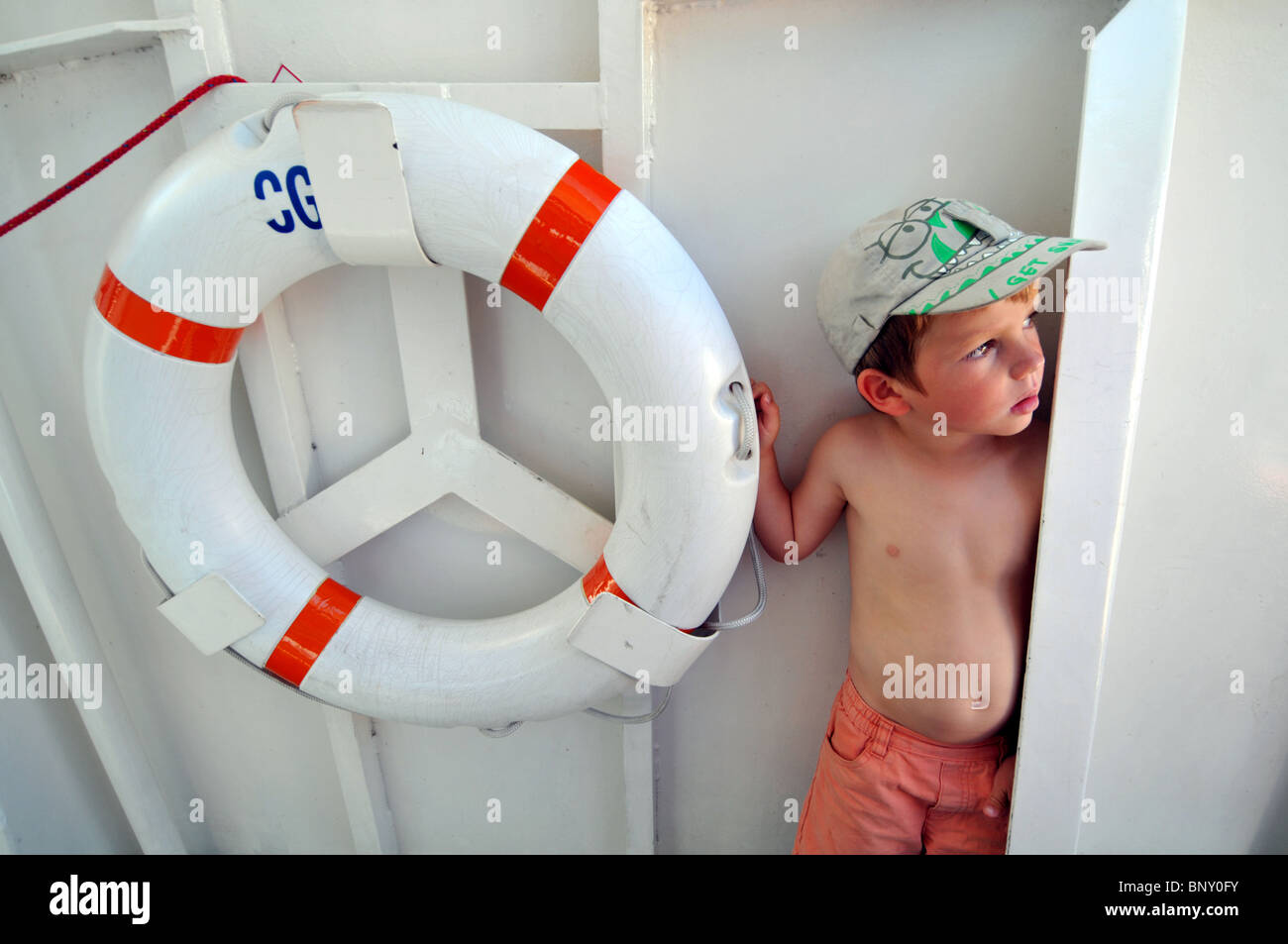 Rettungsring, Kind auf einem Boot neben einem Rettungsring Stockfoto