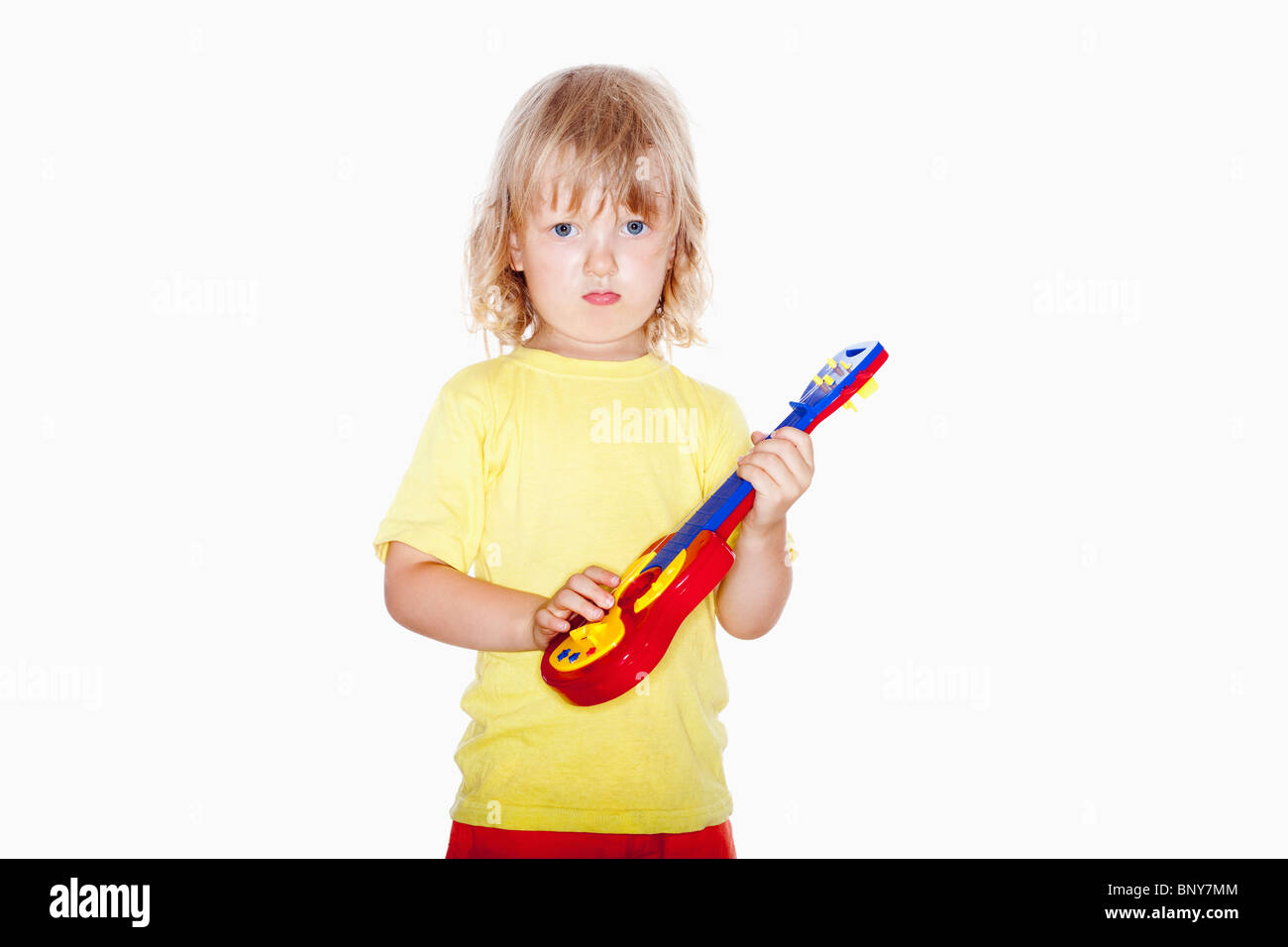 Junge mit langen blonden Haaren spielen mit Spielzeug-Gitarre - isoliert auf weiss Stockfoto