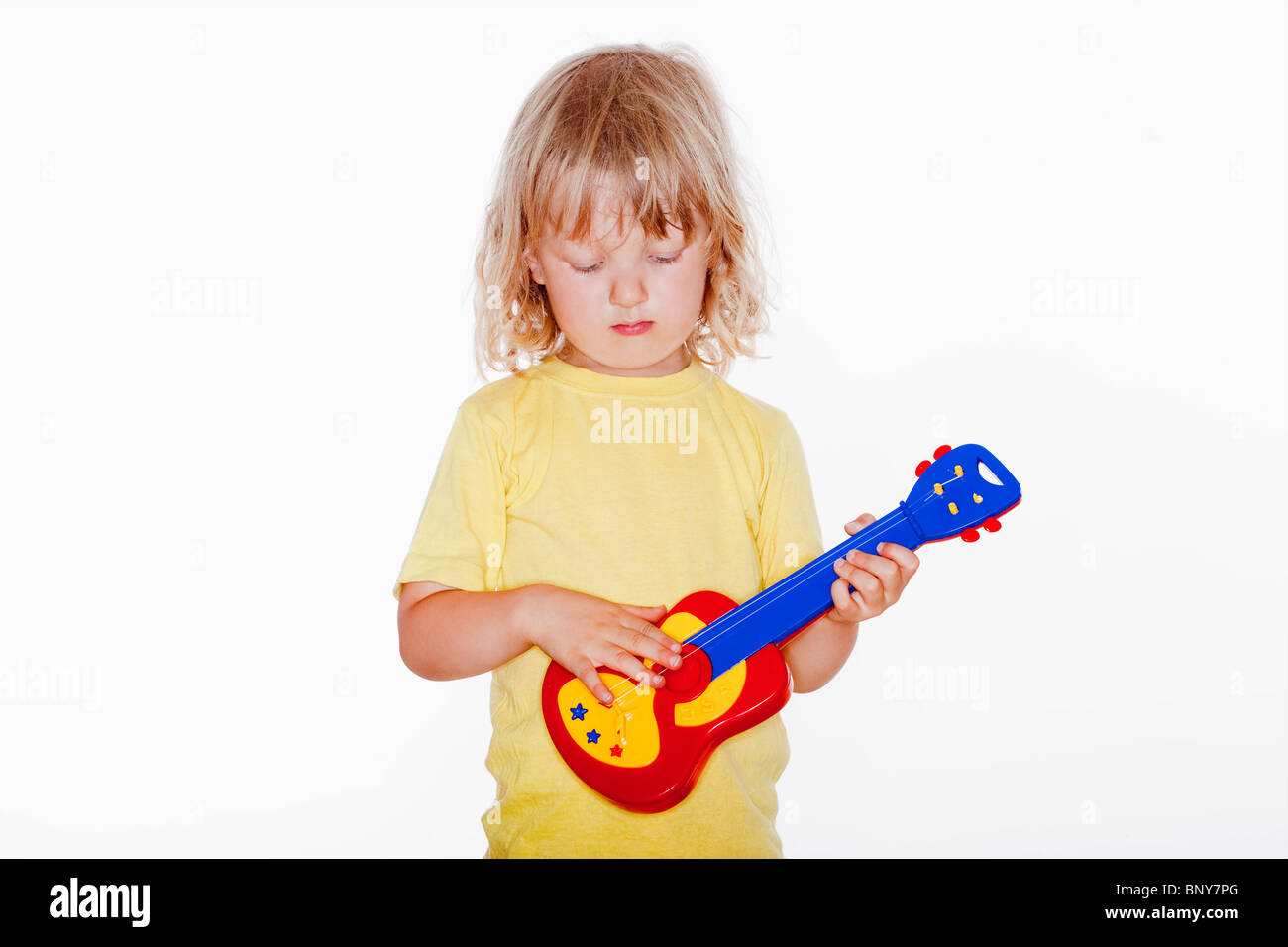 Junge mit langen blonden Haaren spielen mit Spielzeug-Gitarre - isoliert auf weiss Stockfoto