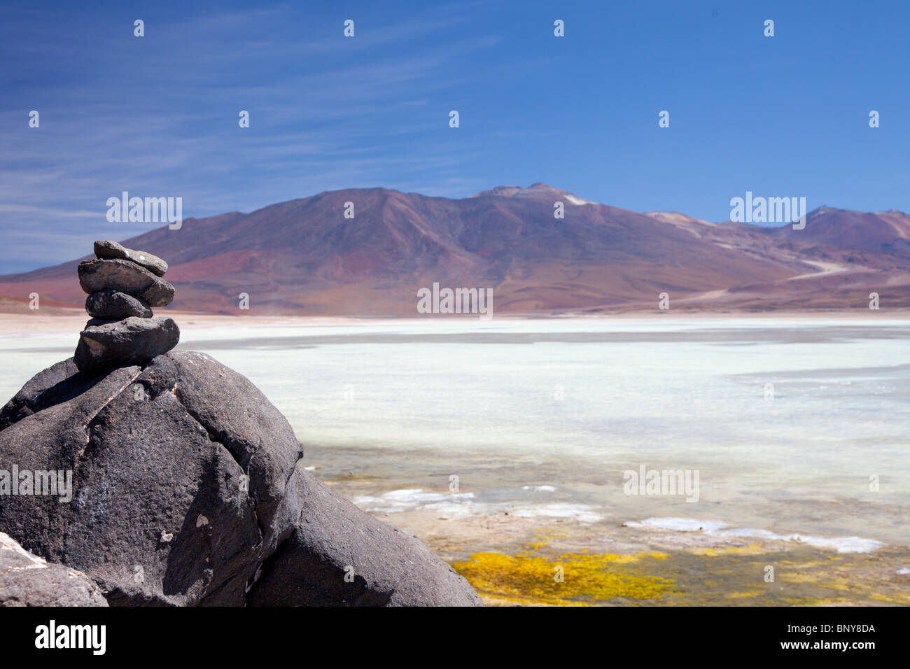 Steinen aufgeschichtet in der bolivianischen Wüste, mit einem See im Hintergrund Stockfoto