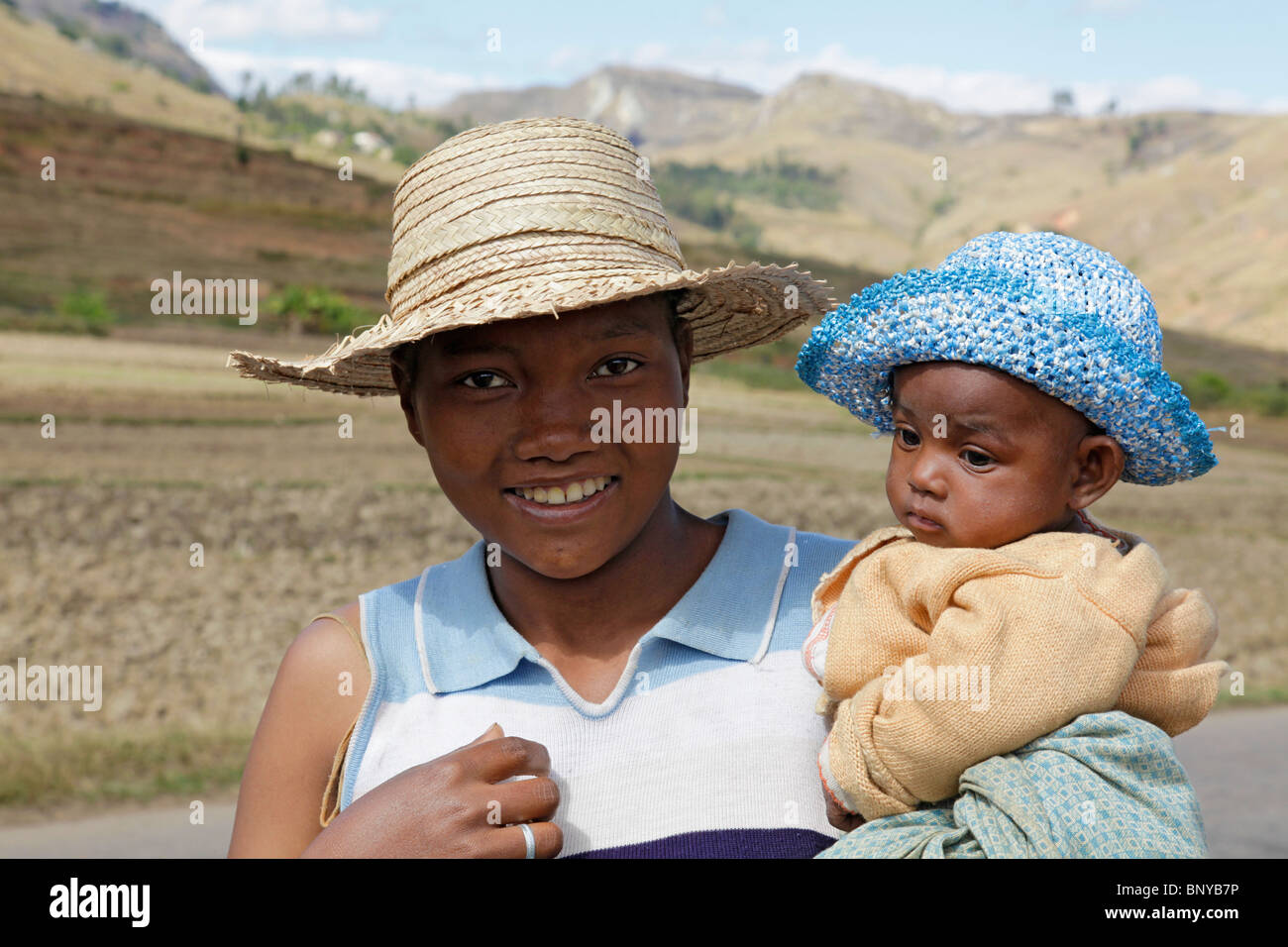 Eine lächelnde junge Antemoro Frau und ein Baby in Bast Sonnenhüte in der Nähe von Ambalavao, Haute Matsiatra, Süd-Ost-Madagaskar Stockfoto