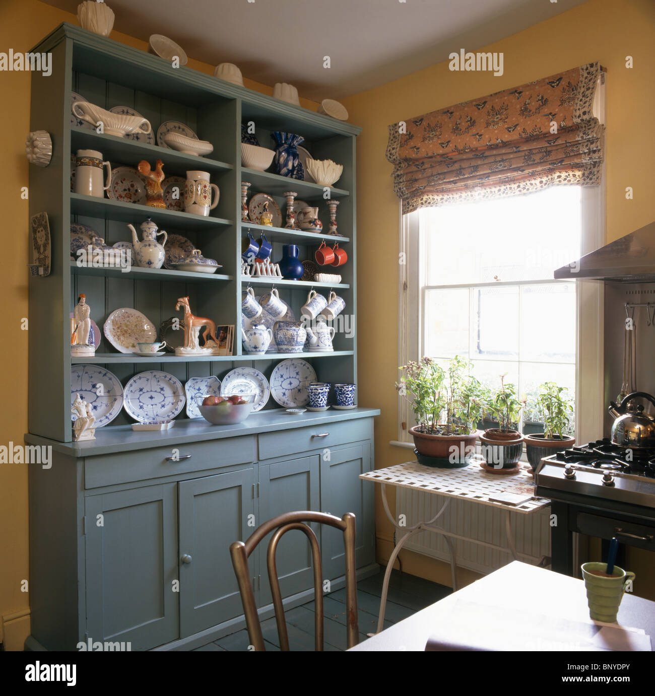 Blau grün Kommode mit Geschirr auf den Regalen in traditionellen Küche  Esszimmer mit gemusterten Rollo am Fenster Stockfotografie - Alamy