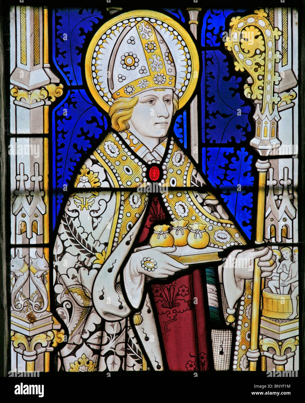 Ein Buntglasfenster von Geoffrey Webb, das den Heiligen Nikolaus von Myra mit drei Säcken Gold zeigt, All Saints Church, Ladbroke, Warwickshire Stockfoto