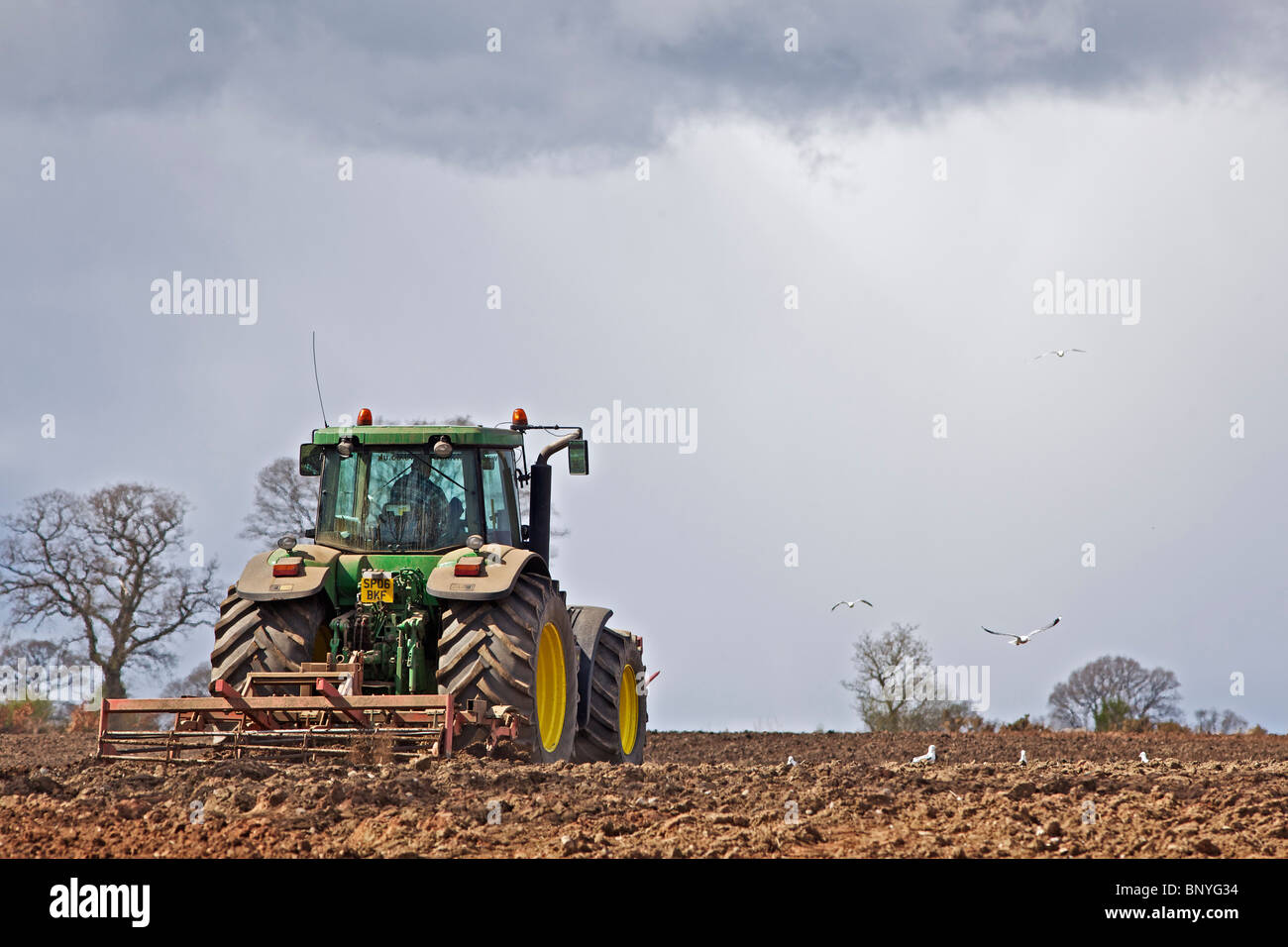 John Deere Traktor Eggen ein Feld in Perthshire Stockfoto