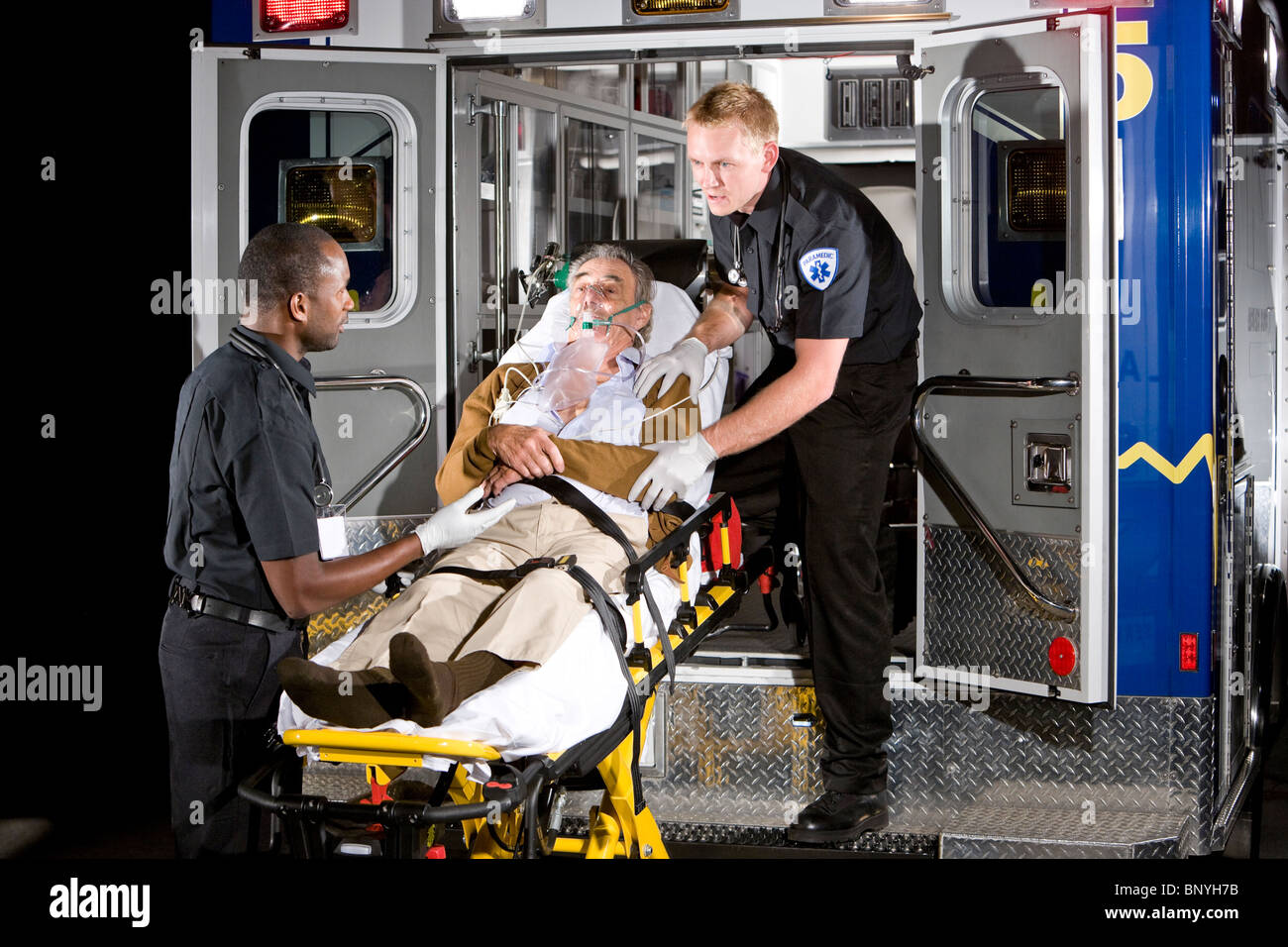 Sanitäter, die Fürsorge für ältere Patienten auf Bahre in Ambulanz in der Nacht Stockfoto