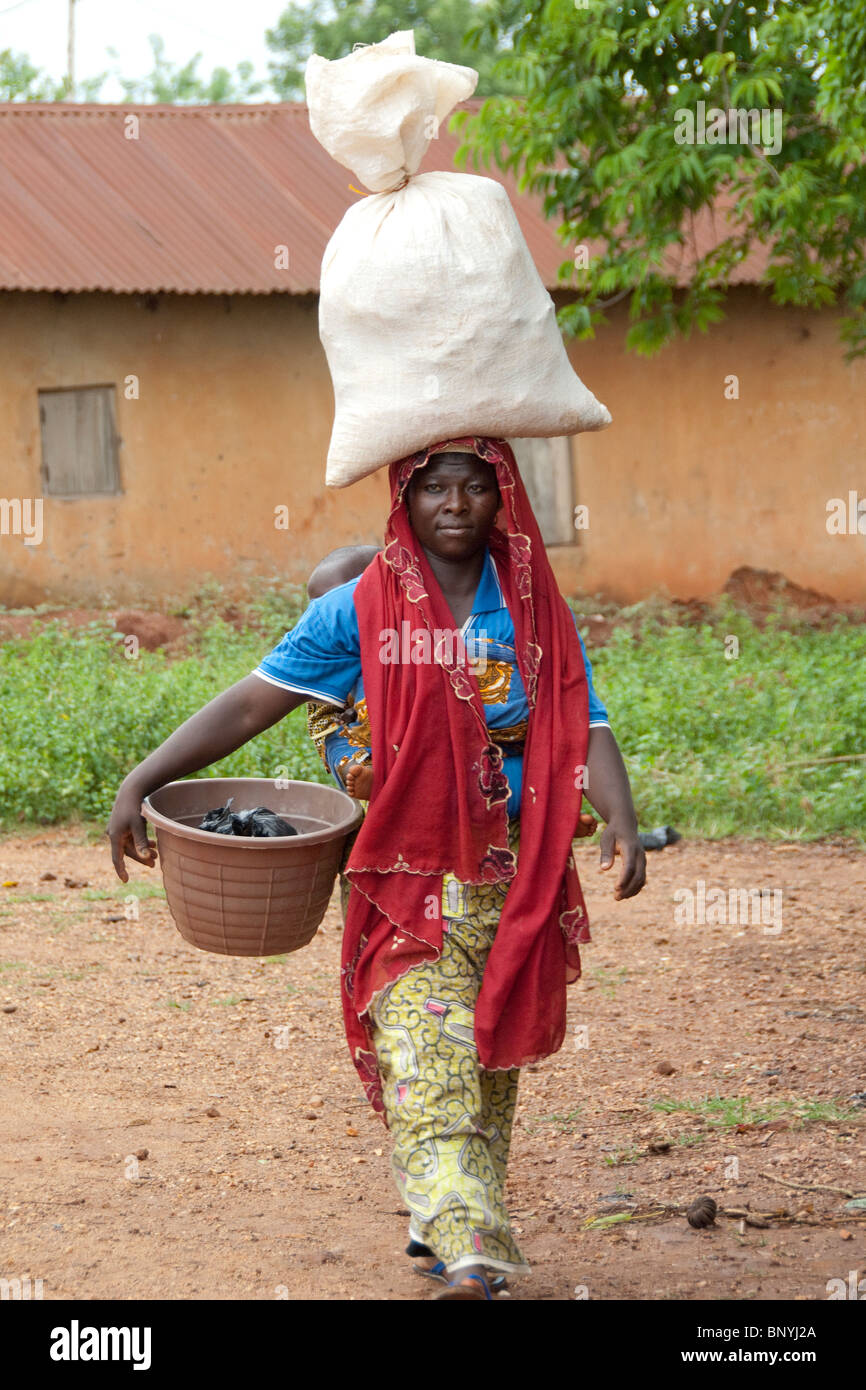 Afrika, Togo, Kpalime Tal. Togoische Bauerndorf. Frau im bunten Gewand mit Last auf Kopf. Stockfoto