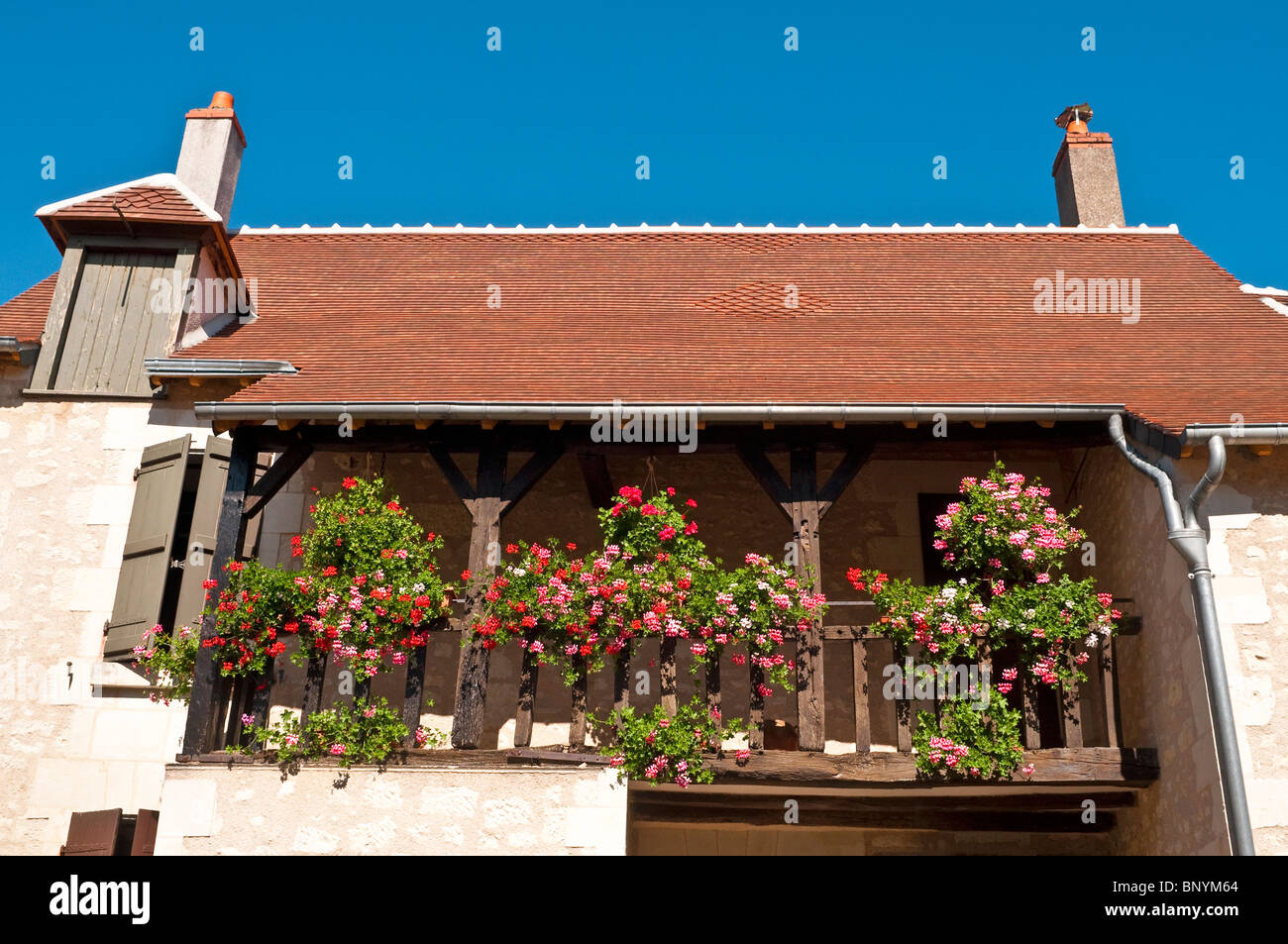 Hängende Körbe und Pflanzer auf Holzbalkon renoviertes Steinhaus - Frankreich. Stockfoto