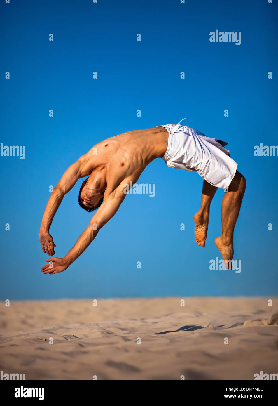 Junger Mann am Strand springen. Stockfoto