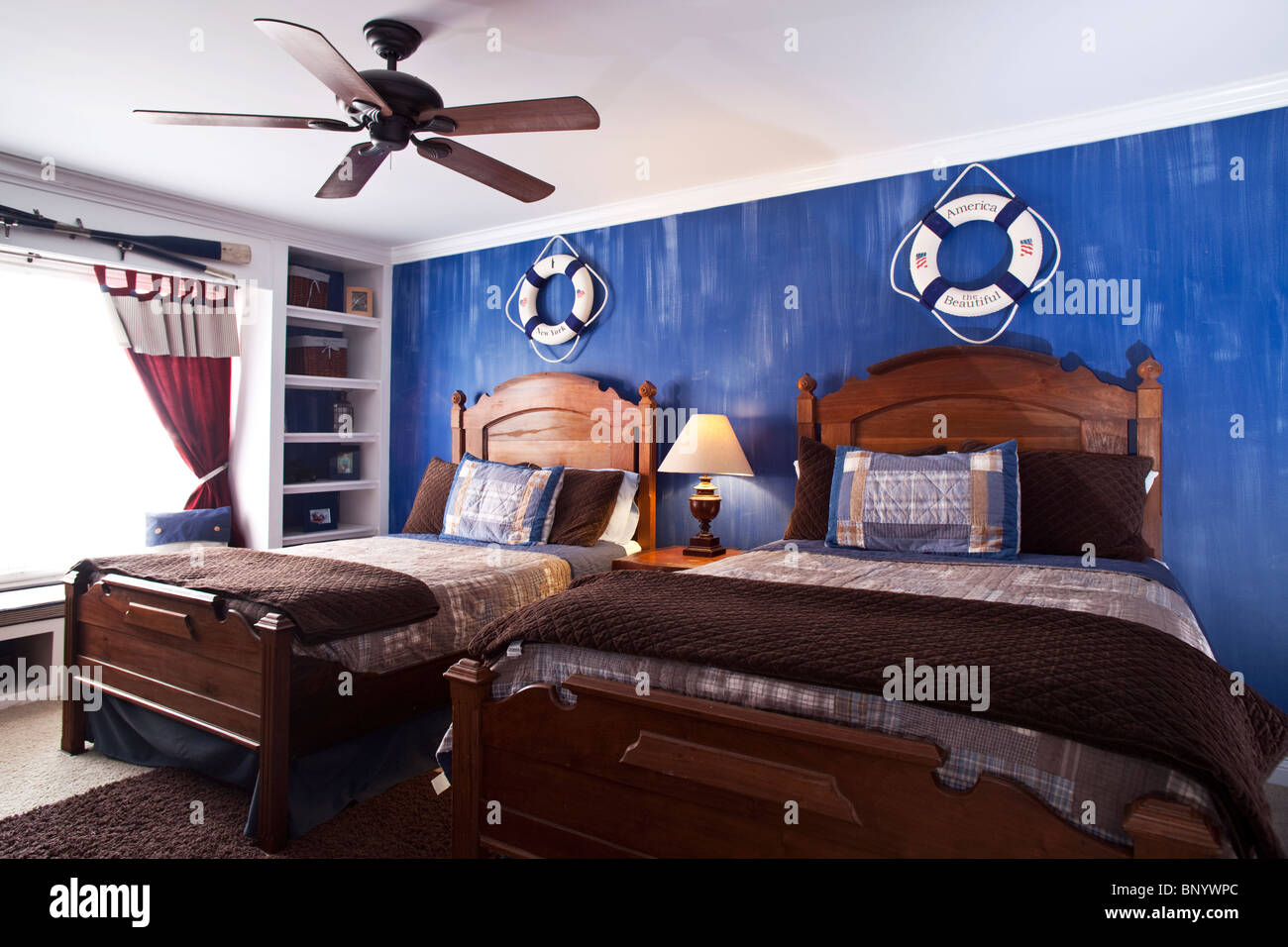 Kinderschlafzimmer mit zwei Betten, hölzerne Landhausmöbel Bücherregal und dekoriert mit Segelausrüstung Stockfoto
