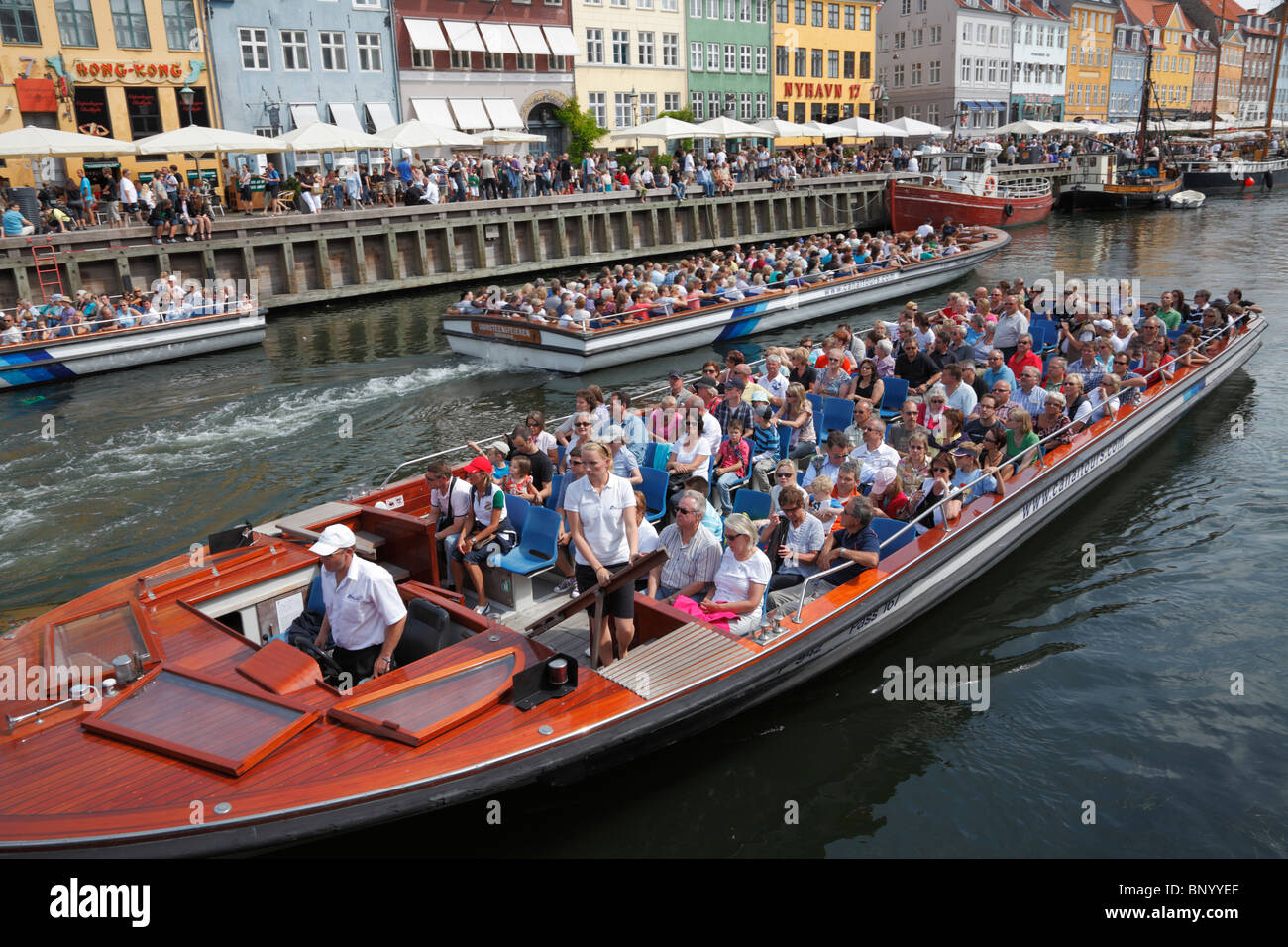 Nyhavn voll von überfüllten Canal Cruise Boote und Besucher und Touristen an der Wasserseite und Straßencafés Restaurants auf einem sehr warmen und langen Sommer Tag Stockfoto