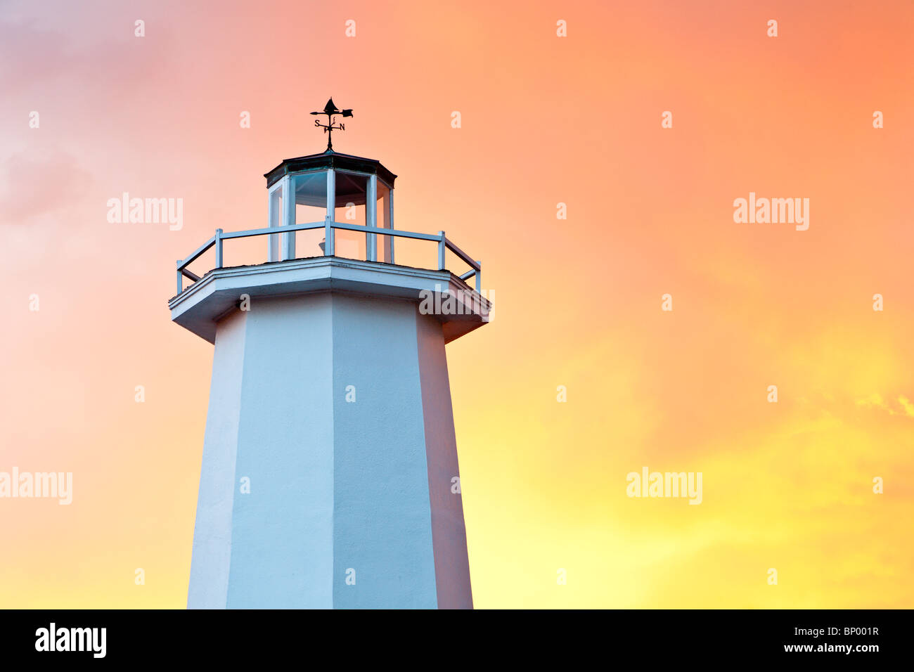 Dramatischer gelben und orangefarbenen Himmel hinter einer weißen Replik eines Leuchtturms über Einzelhandel Souvenirläden in Tarpon Springs, Florida Stockfoto