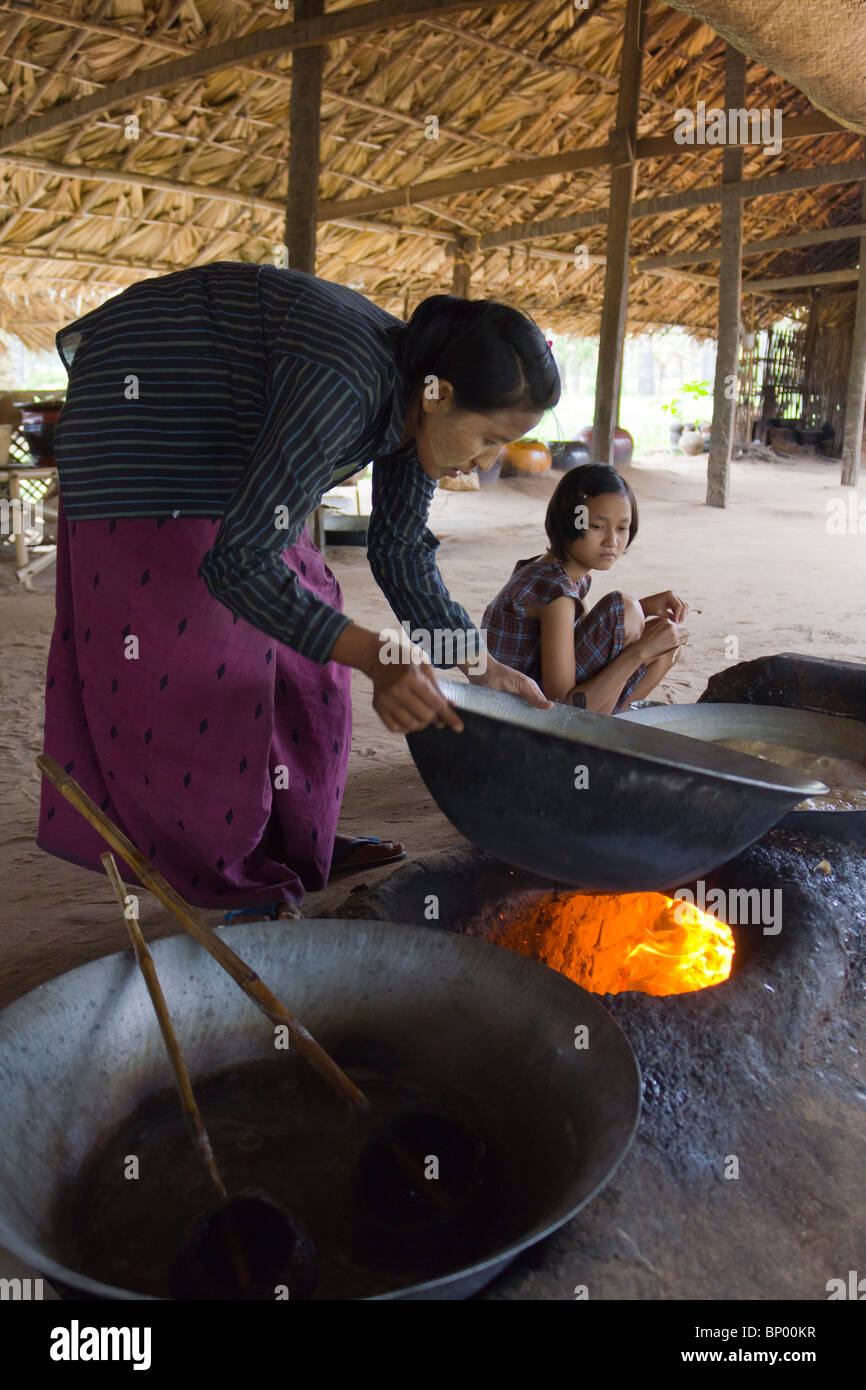 Frau Gießen Sap erhitzt auf Feuer gesammelt von Palmyra oder Toddy Palm zu Palm Zucker, in der Nähe von Bagan, Myanmar Stockfoto