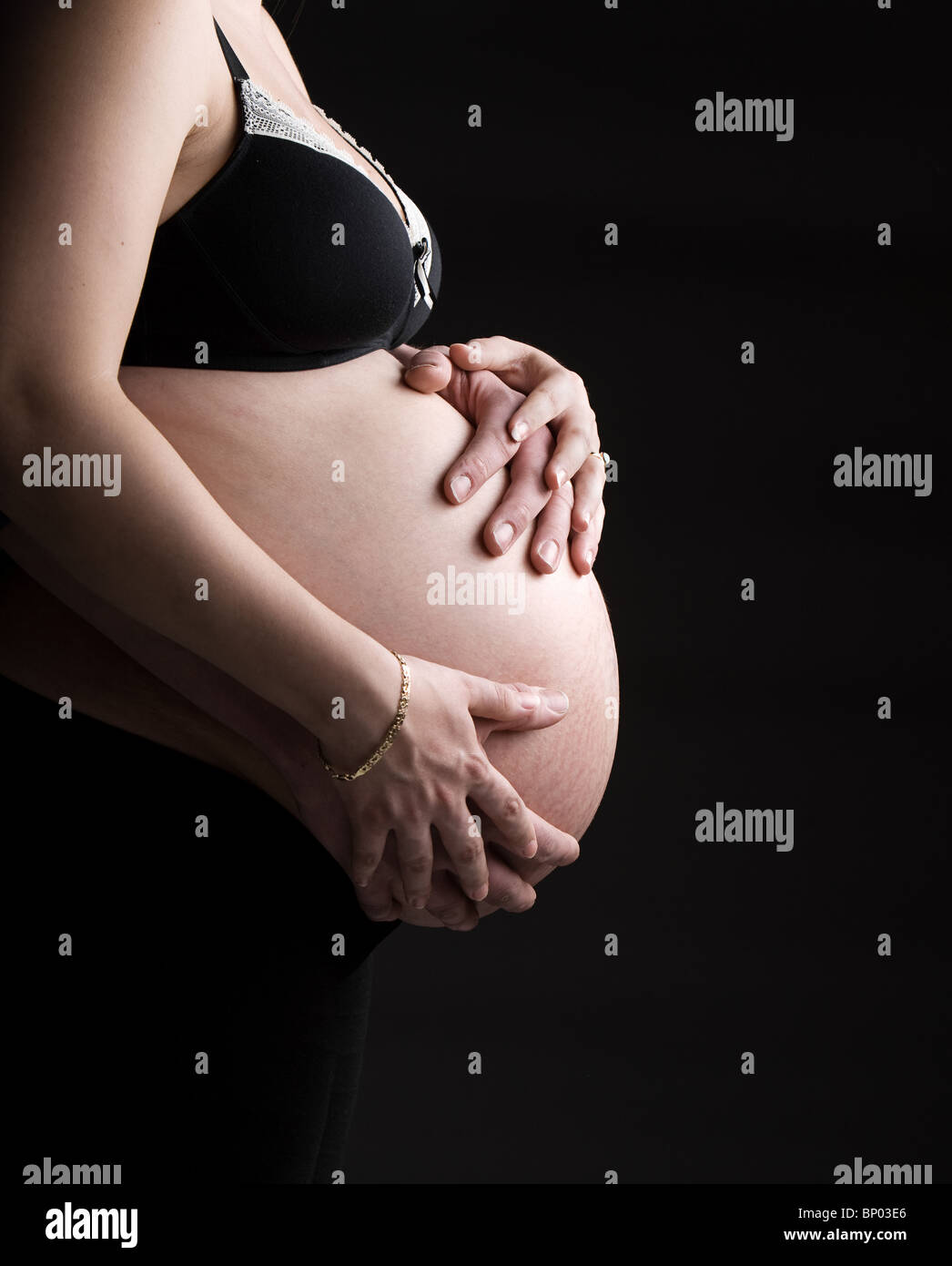Schuss der Mutter und des Vaters Hände unterstützen schwangere Bump Stockfoto