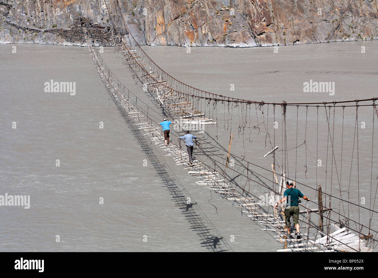 Pakistan - Karakorum - Hunza-Tal - Touristen eine Hängebrücke über den Hunza-Fluss überqueren Stockfoto