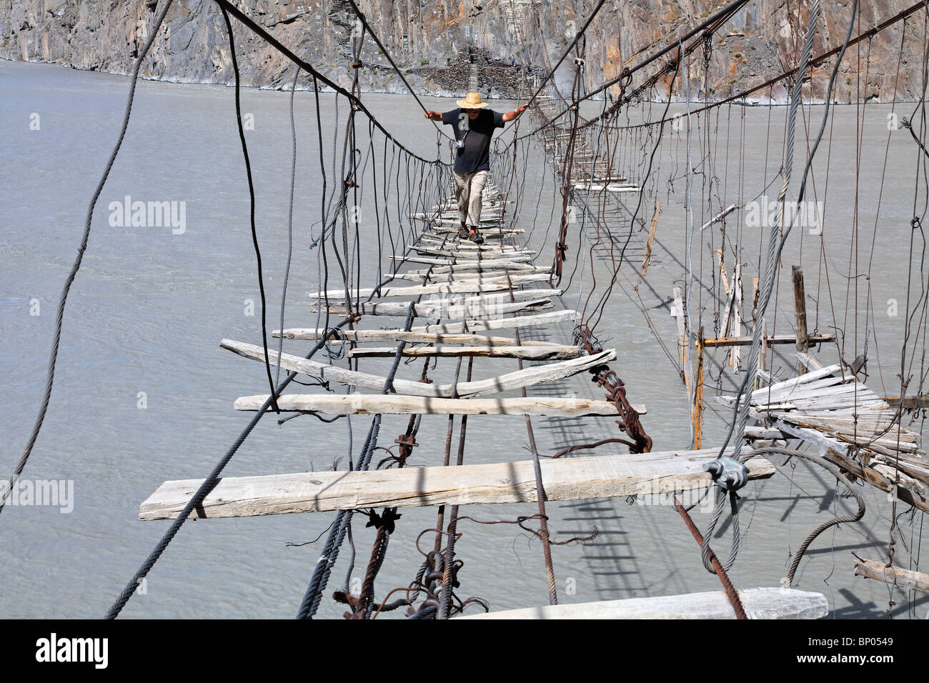 Pakistan - Karakorum - Hunza-Tal - Tourist Überquerung einer Hängebrücke über den Hunza-Fluss Stockfoto