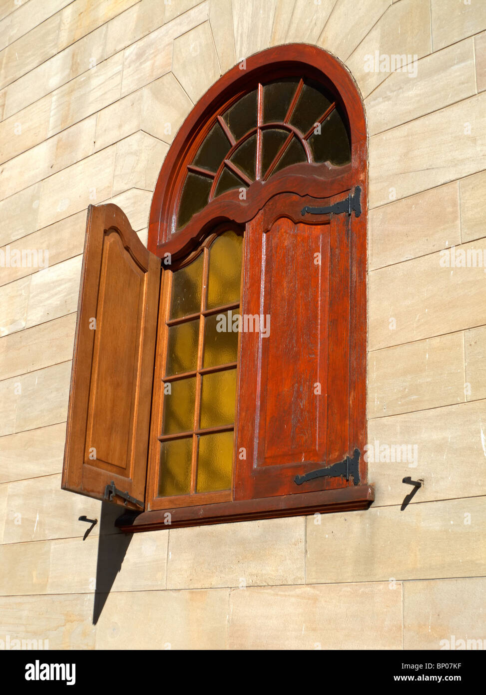 Dekoratives Fenster in einem Holzrahmen mit Sandsteinmauern Stockfoto