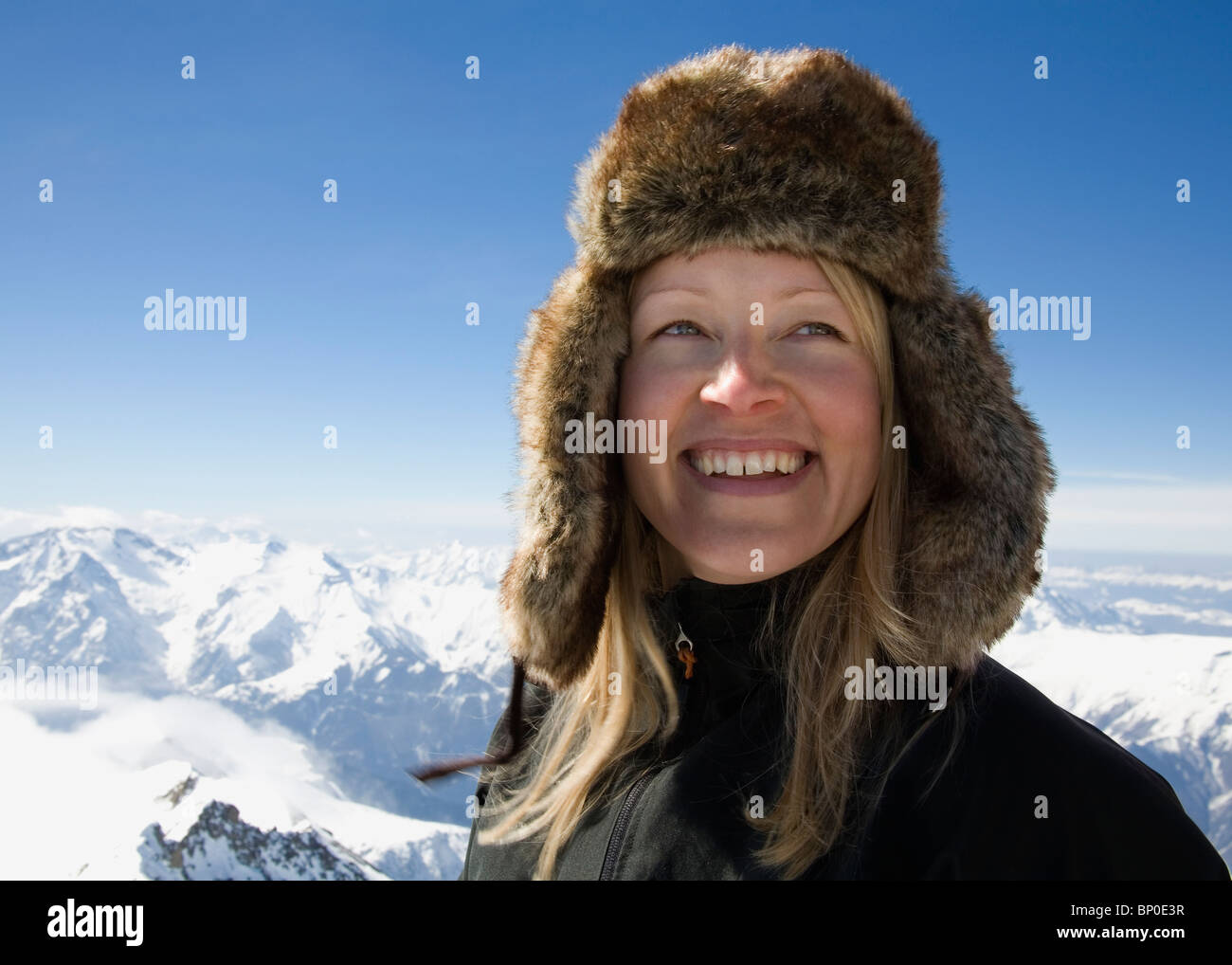Frau mit Pelzmütze auf Berggipfel Stockfoto