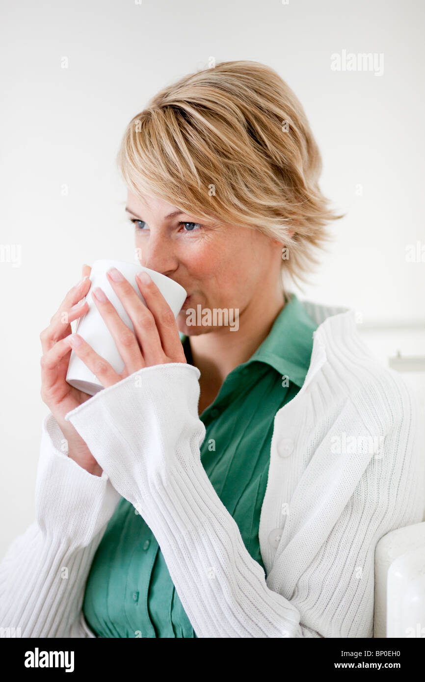 Junge Frau zu Hause trinken aus der Tasse Stockfoto