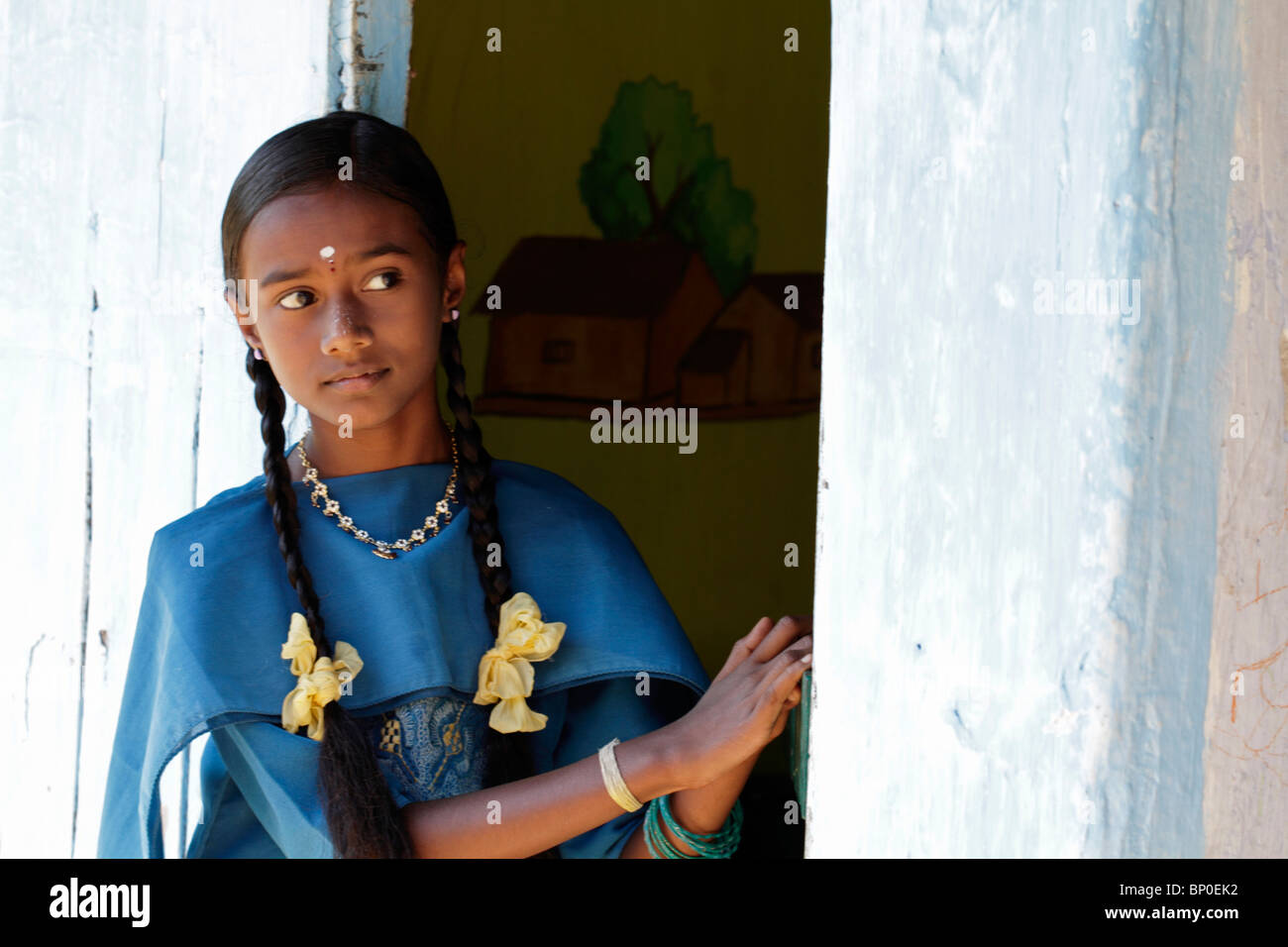 Indien, Süd-Indien, Kerala. Eine junge Inderin schaut aus der Tür von einem Tee Planters Haus in der Nähe von Munnar. Stockfoto