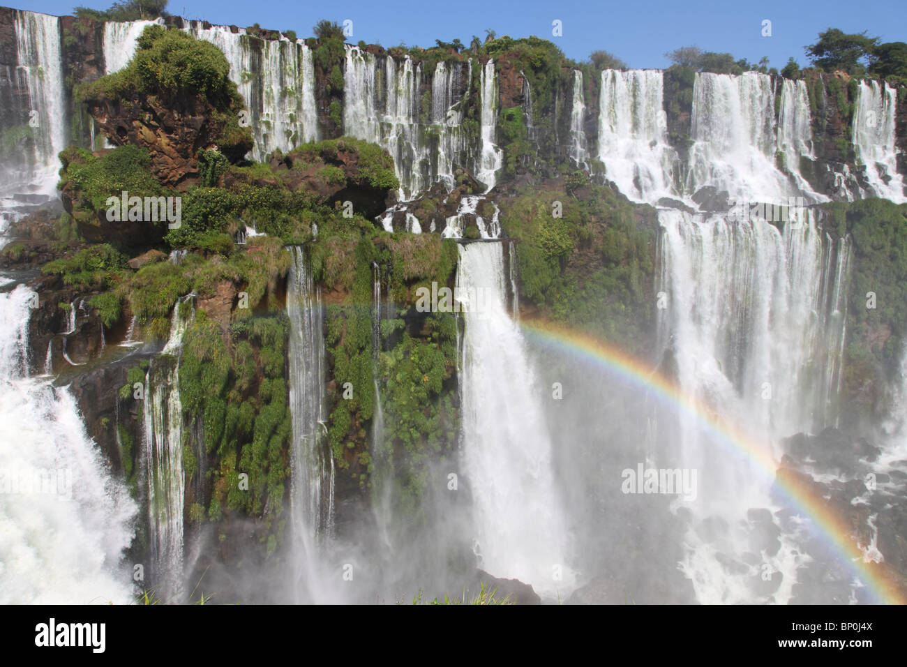 Iguazu Wasserfälle mit Regenbogen an einem sonnigen Tag. Der größte Wasserfall auf der Erde Stockfoto