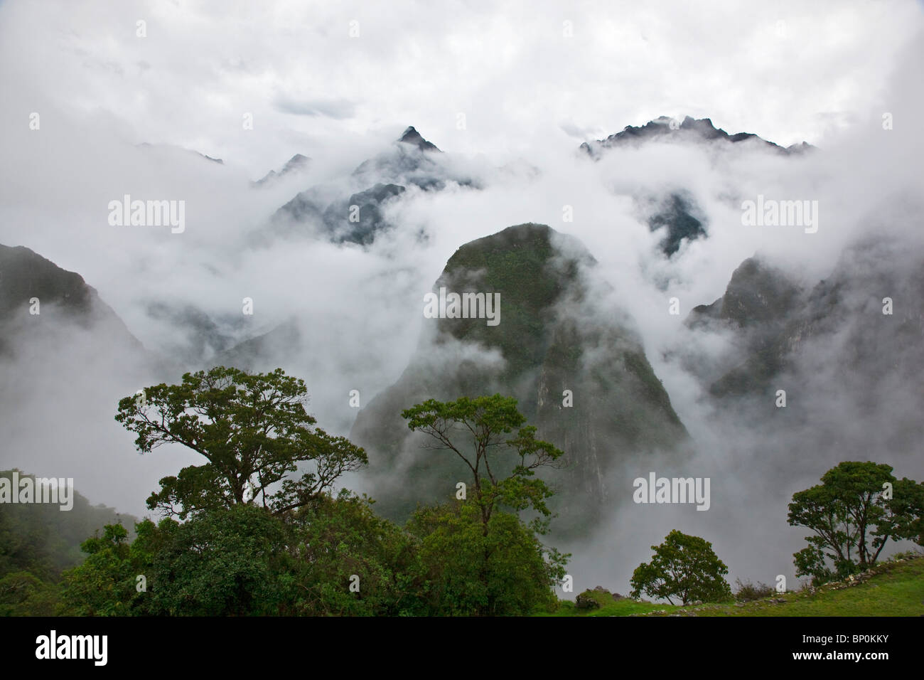 Peru, In den frühen Morgenstunden geringer Nebel und Wolken steigen aus den steilen Tälern rund um die Inka-Ruinen in Machu Picchu. Stockfoto