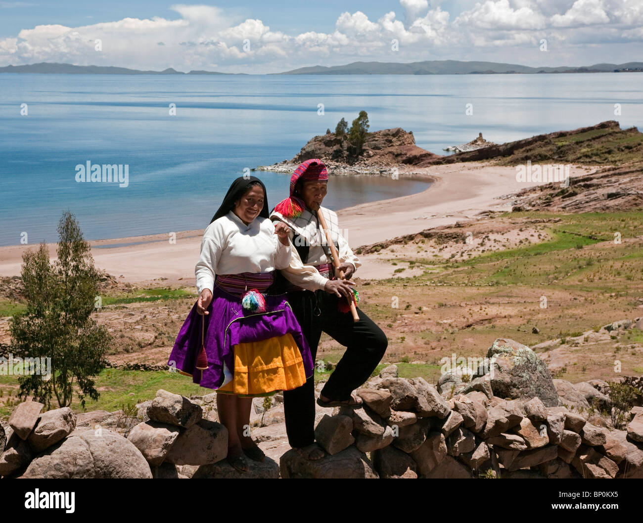 Peru, spielt A Quechua sprechenden Mann seine Querflöte auf Taquile Insel, während seine Frau Wolle dreht. Stockfoto