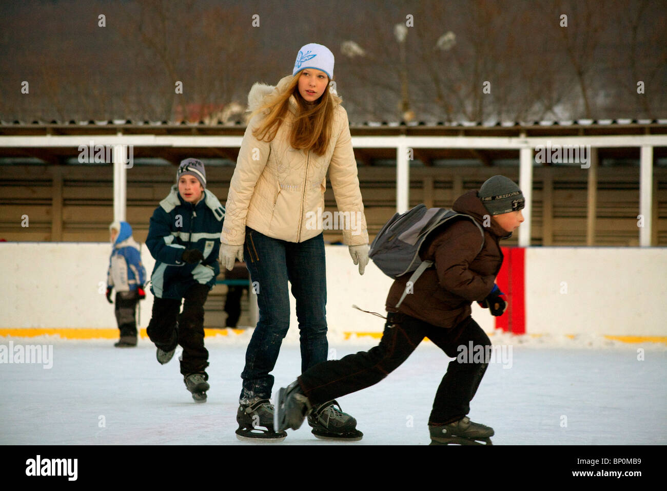 Russland, Fernost, Sachalin; Juschno-Sachalinsk; Eine Frau und Kinder Eislaufen auf einem Amateur Eishockey in der Stadt Stockfoto