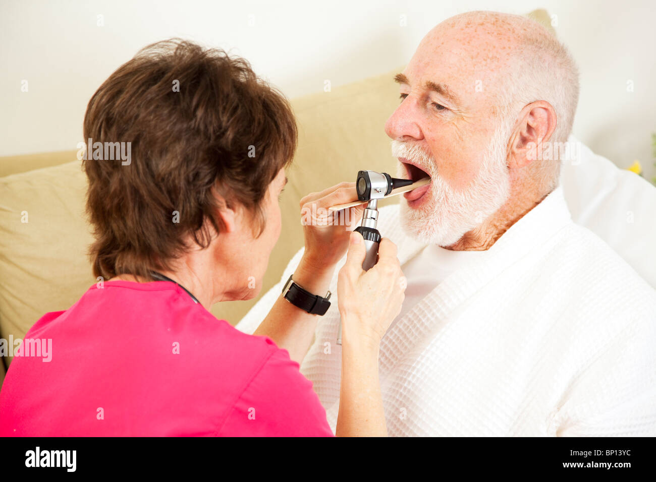 Home Gesundheit Krankenschwester prüft ein Patient Kehle mit einem Otoskop. Stockfoto