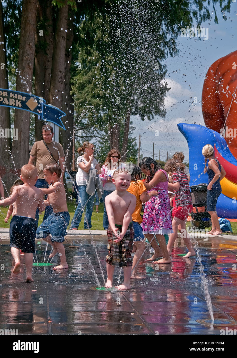 Diese vertikale redaktionelle stock Foto sind niedliche kleine Kinder spielen im Sommer in einem Brunnen mit vielen Wassertropfen. Stockfoto