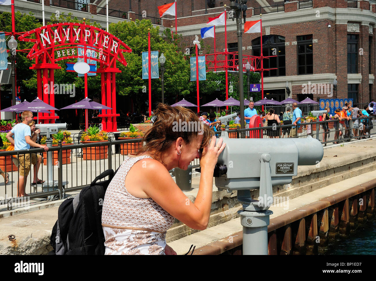 Blick auf Lake Michigan durch Pay-Teleskop am Navy Pier Chicago Frau. Beer Garden & Ausstellungshalle im Hintergrund. Stockfoto