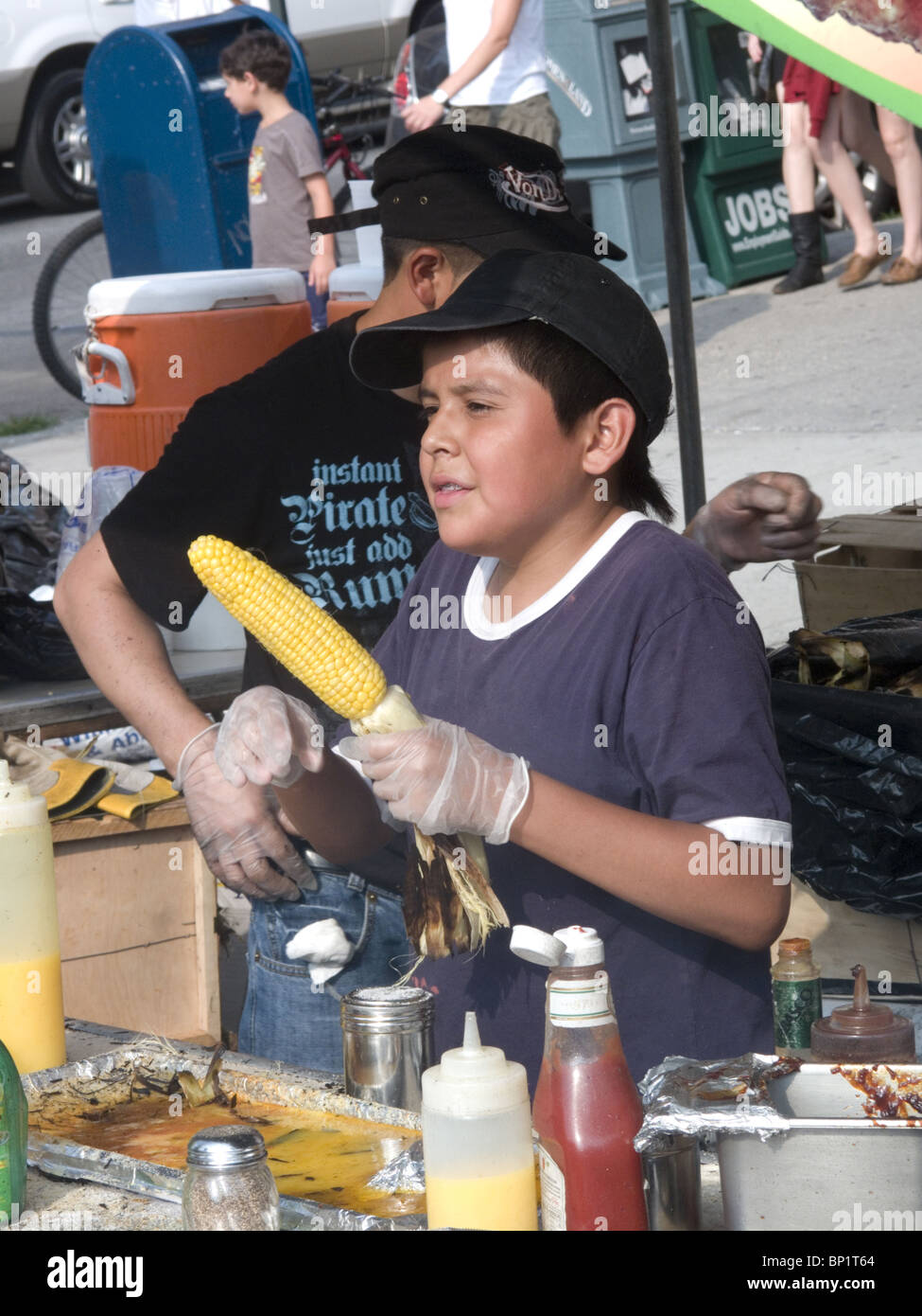 Mexikanische junge verkauft gegrilltem Mais auf der 7. Himmel Straße Messe in Park Slope, Brooklyn, NY. Stockfoto