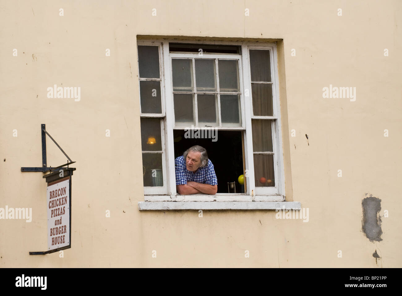 Mann aus offenen Flügel Fenster gerade Parade durch die Brecon Stadt während Brecon Jazz Festival 2010 Stockfoto