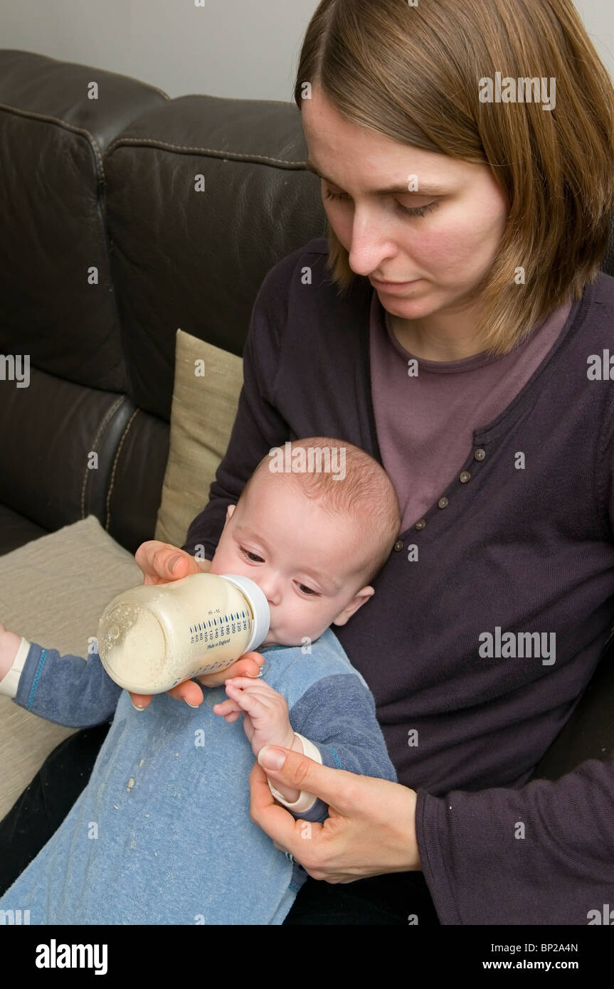 Eloi - 6 Monate - Essen aus seinem feed Flasche unterstützt durch seine Mutter Stockfoto